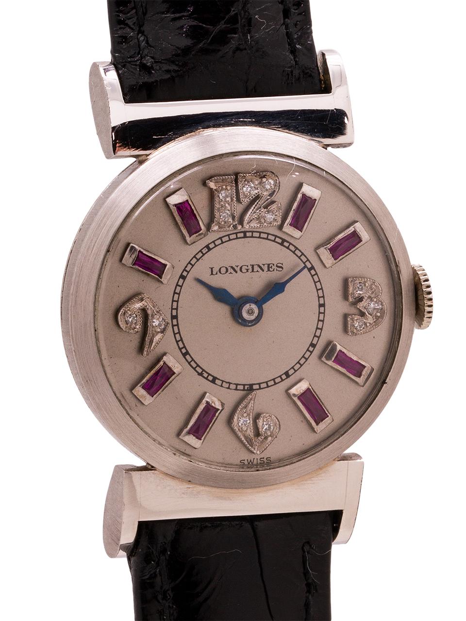 
Lady Longines platinum diamond and ruby set watch circa 1950’s. 26 x 36 mm platinum case with square extended lugs, and snap caseback. Featuring an interesting and beautiful silver satin dial with diamond and ruby set hour markers. Powered by the