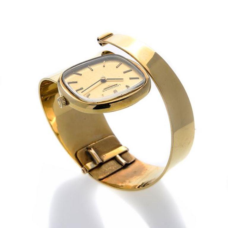 Montre Longines pour dame : cadran doré avec index appliqués en or jaune, lunette lisse, mouvement à remontage manuel et bracelet enveloppant en or jaune.

Cadran 28 mm, diamètre intérieur du bracelet 5,5 cm. 

POIDS : 75,3 g