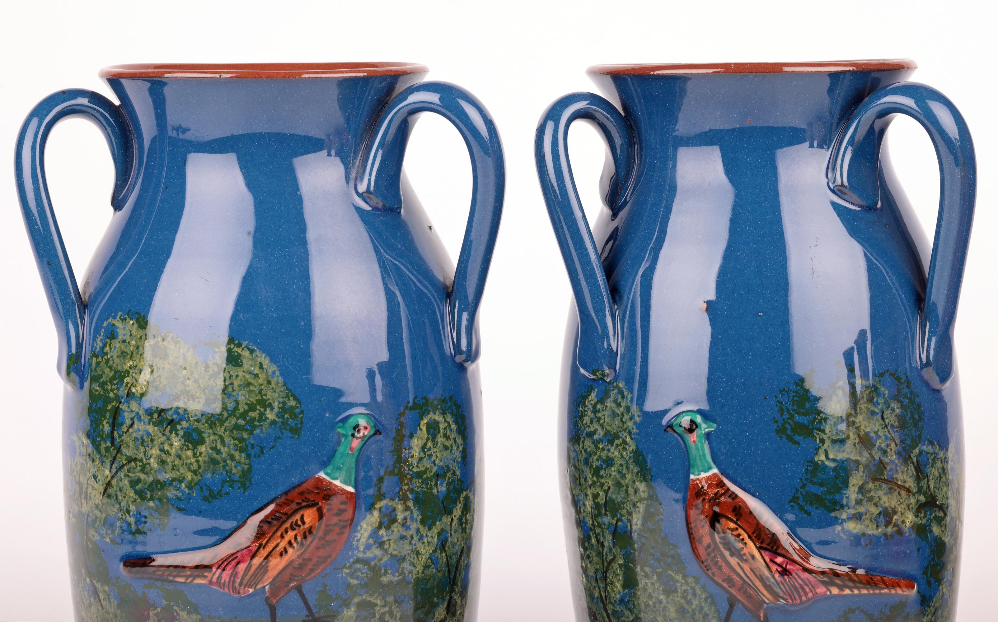A large and impressive pair English Torquay art pottery three handled vases decorated with pheasants by Longpark pottery and dating from the late 19th or early 20th century. 
Established in 1880 Longpark was a significant pottery in the Torquay