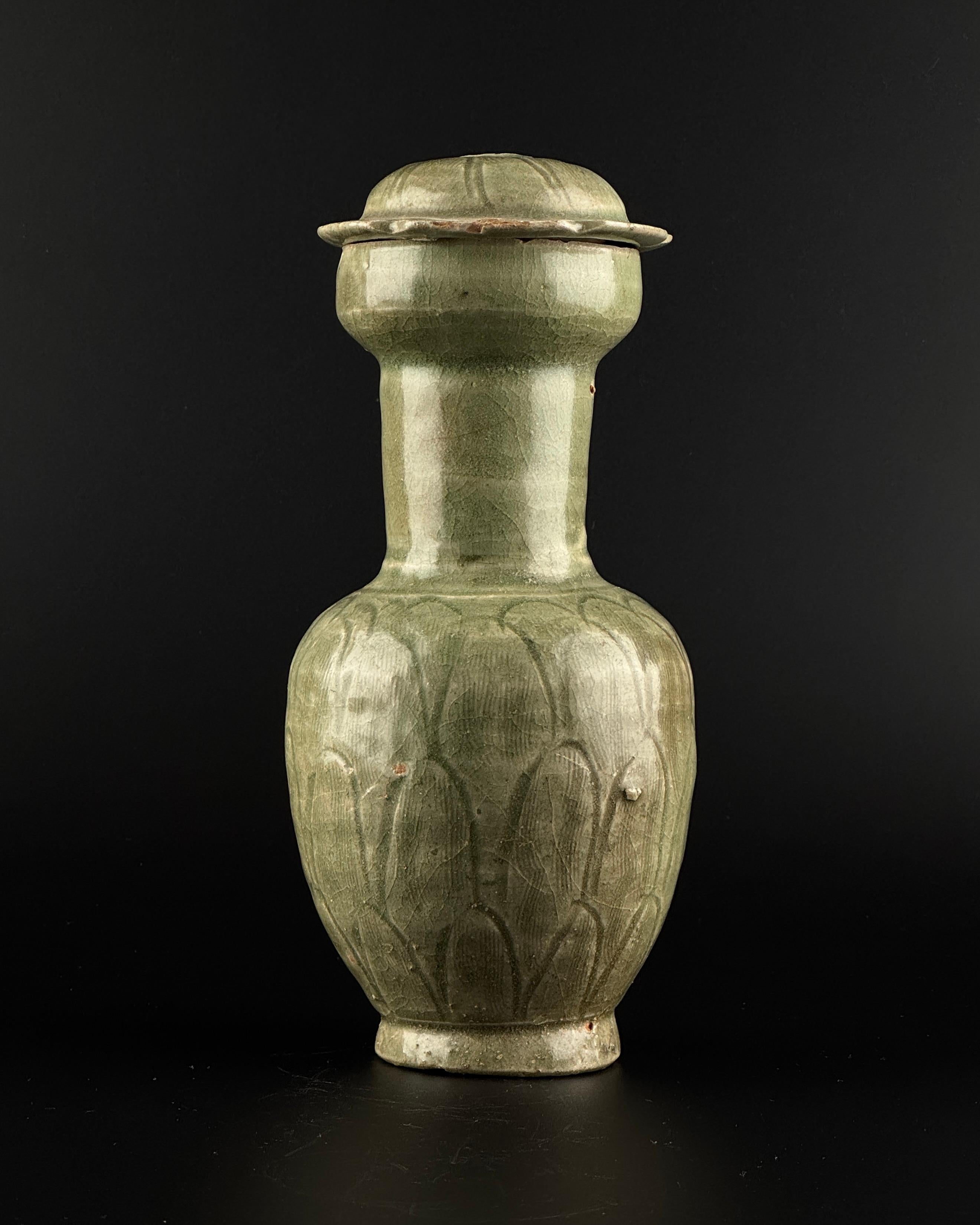 La jarra es de maceta robusta, con un cuerpo ovalado tallado con pétalos de loto superpuestos bajo el cuello recto. Todo ello cubierto de un vidriado craquelado de color verde oliva, a excepción de la base de la jarra. Astillas y restos de oxidación