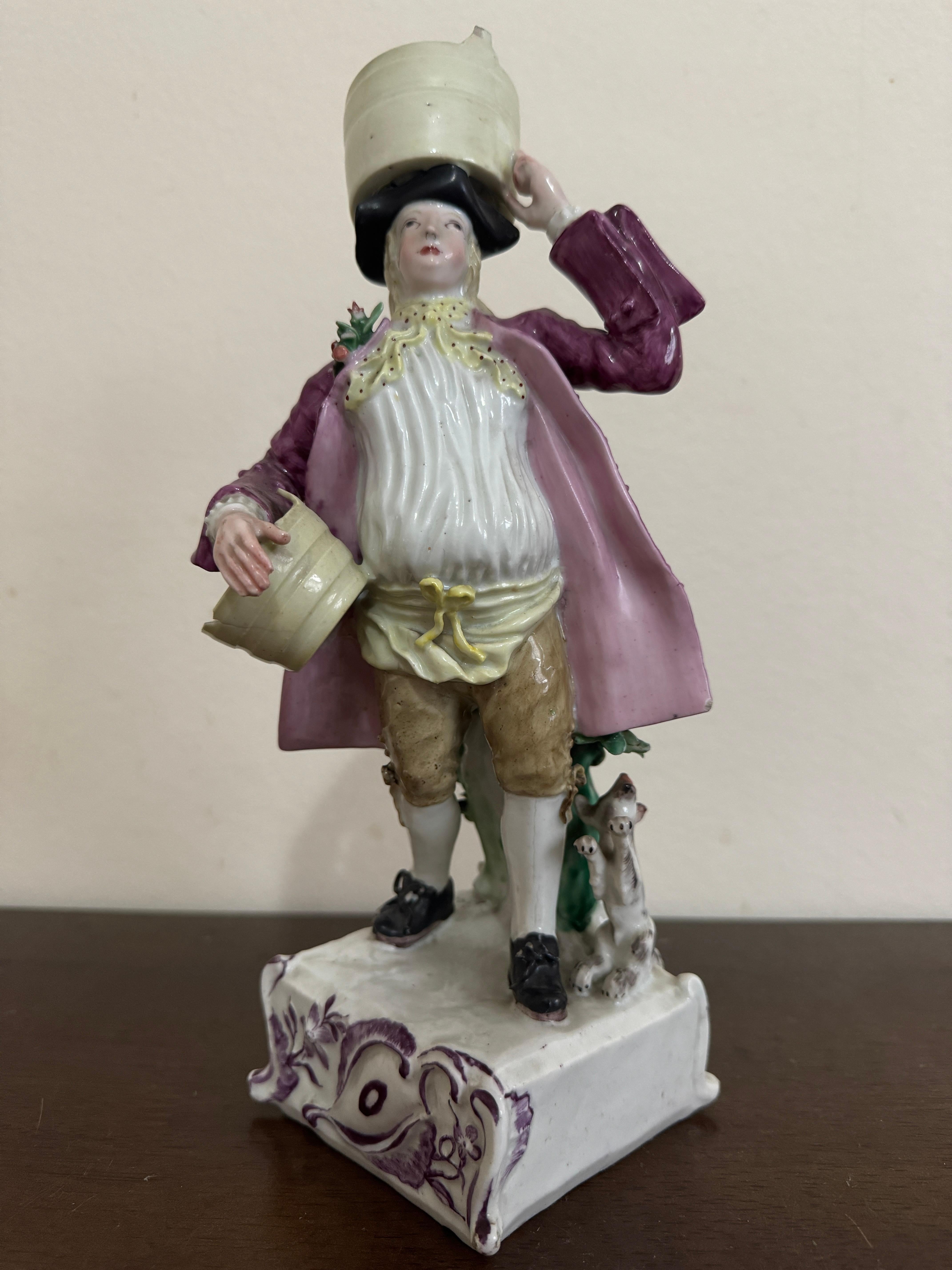 Figura de lechero de Longton Hall, hacia 1755, con dos cubos, uno en la cabeza y el otro a su lado, tocado con sombrero tricornio negro, camisa blanca, pañuelo amarillo y puce moteado, abrigo puce y calzones marrones, de pie ante un tocón de árbol