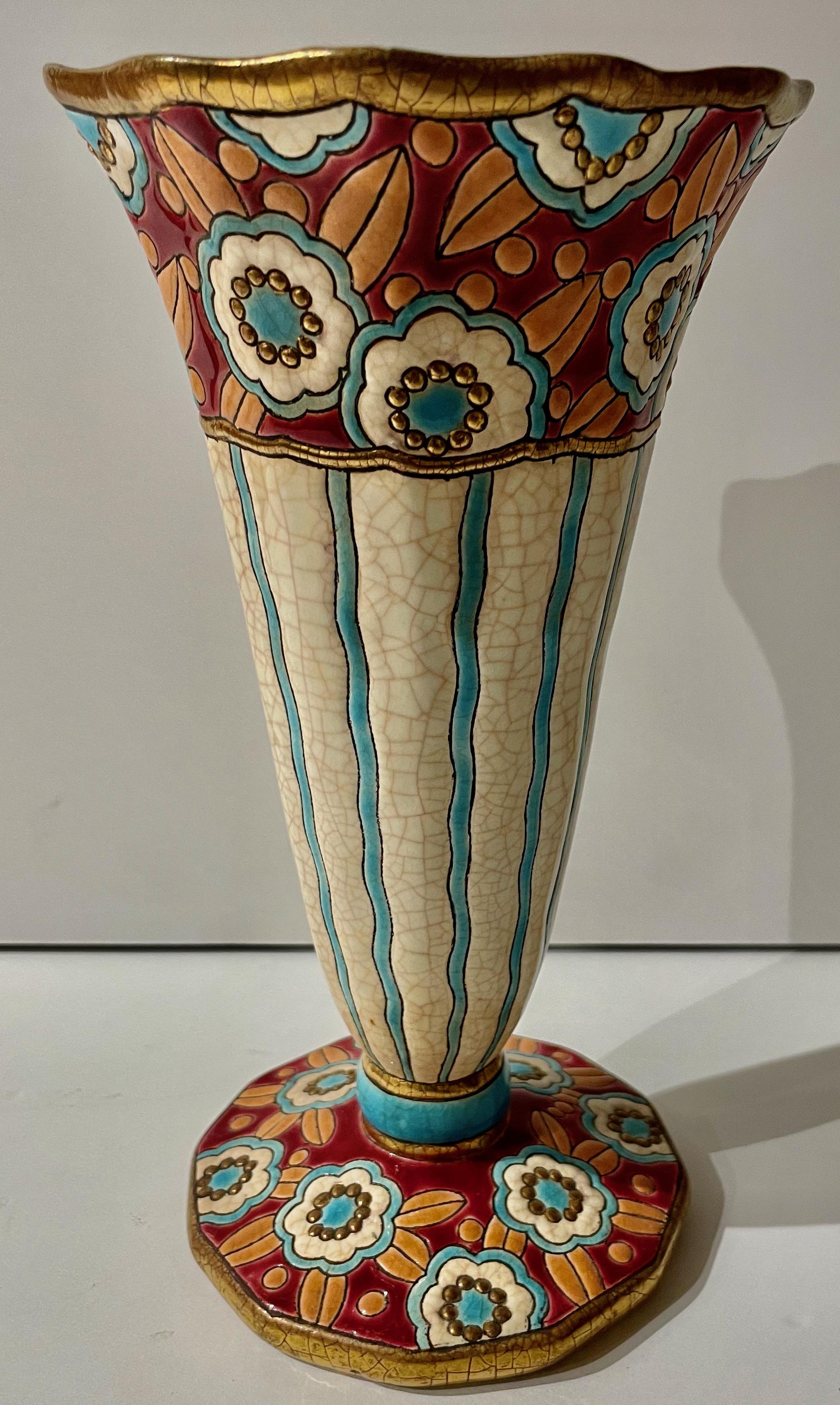 Vase en céramique cloisonnée Art déco français Longwy. Des couleurs étonnantes avec une base facettée avec des fleurs bleues, bordeaux et orange entrecroisées dans le design du vase. Les détails dorés autour de la base et du sommet contribuent à