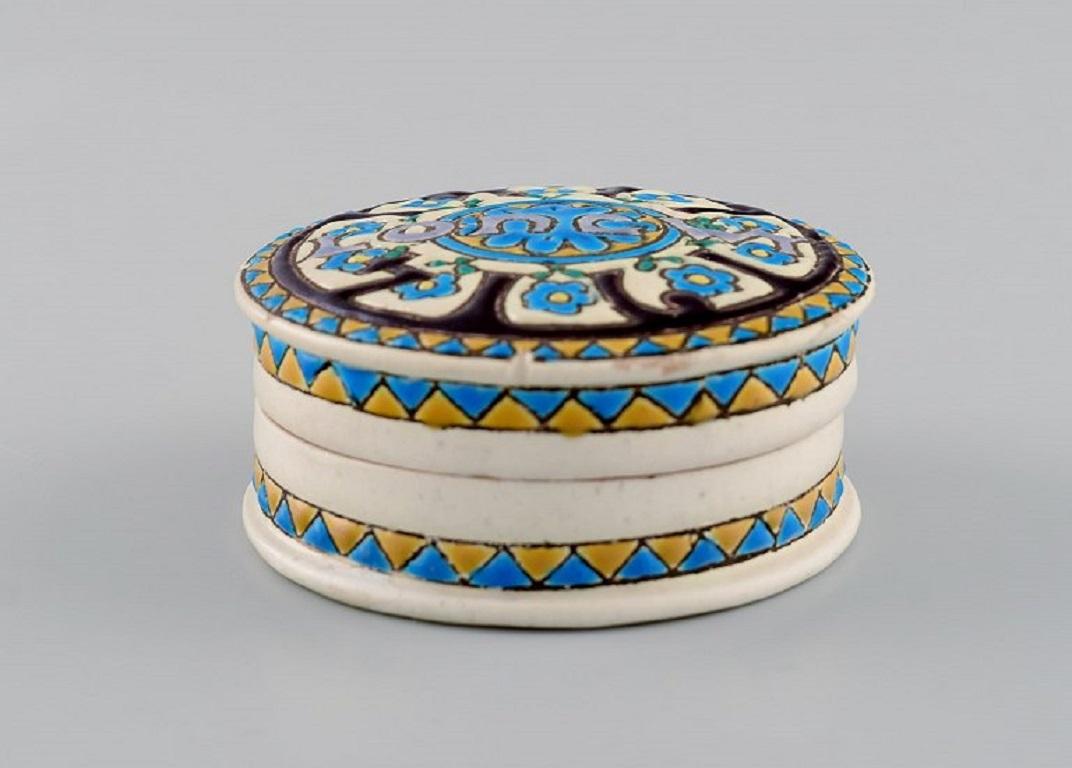 Longwy, France. Art Deco lidded box in glazed stoneware with hand-painted blue flowers and patterned decoration. 
1920s / 30s.
Measures: 7.4 x 3.5 cm.
In excellent condition.
Stamped.

The French town of Longwy, in the region of Lorraine near