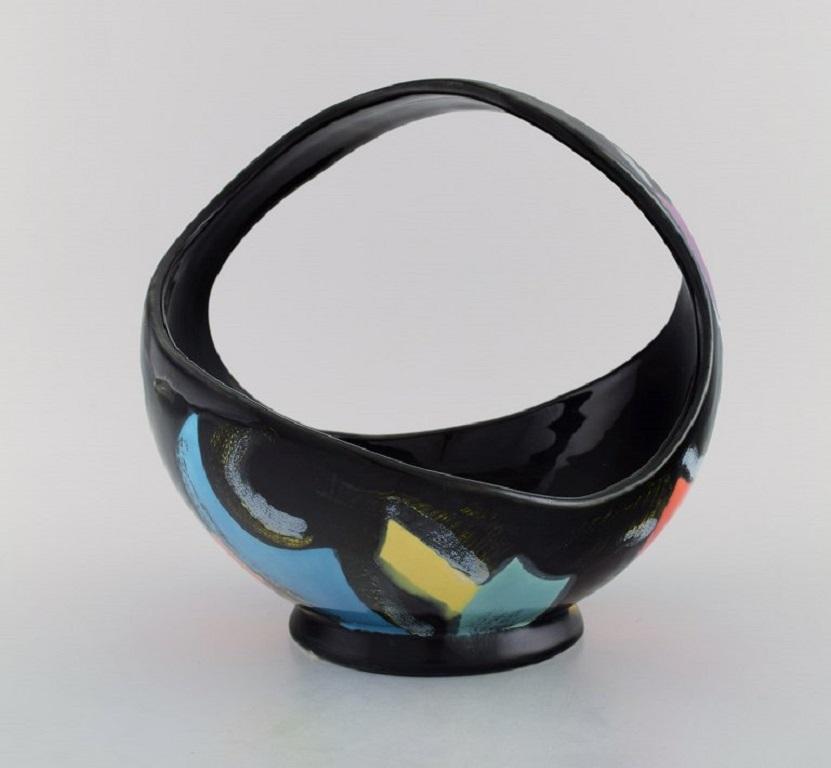 Longwy, Francia. Cestino Equinoxe in ceramica smaltata. Decorazione astratta policroma su sfondo nero. 
Metà del XX secolo.
Misure: 24 x 23 cm.
In ottime condizioni.
Timbrato.