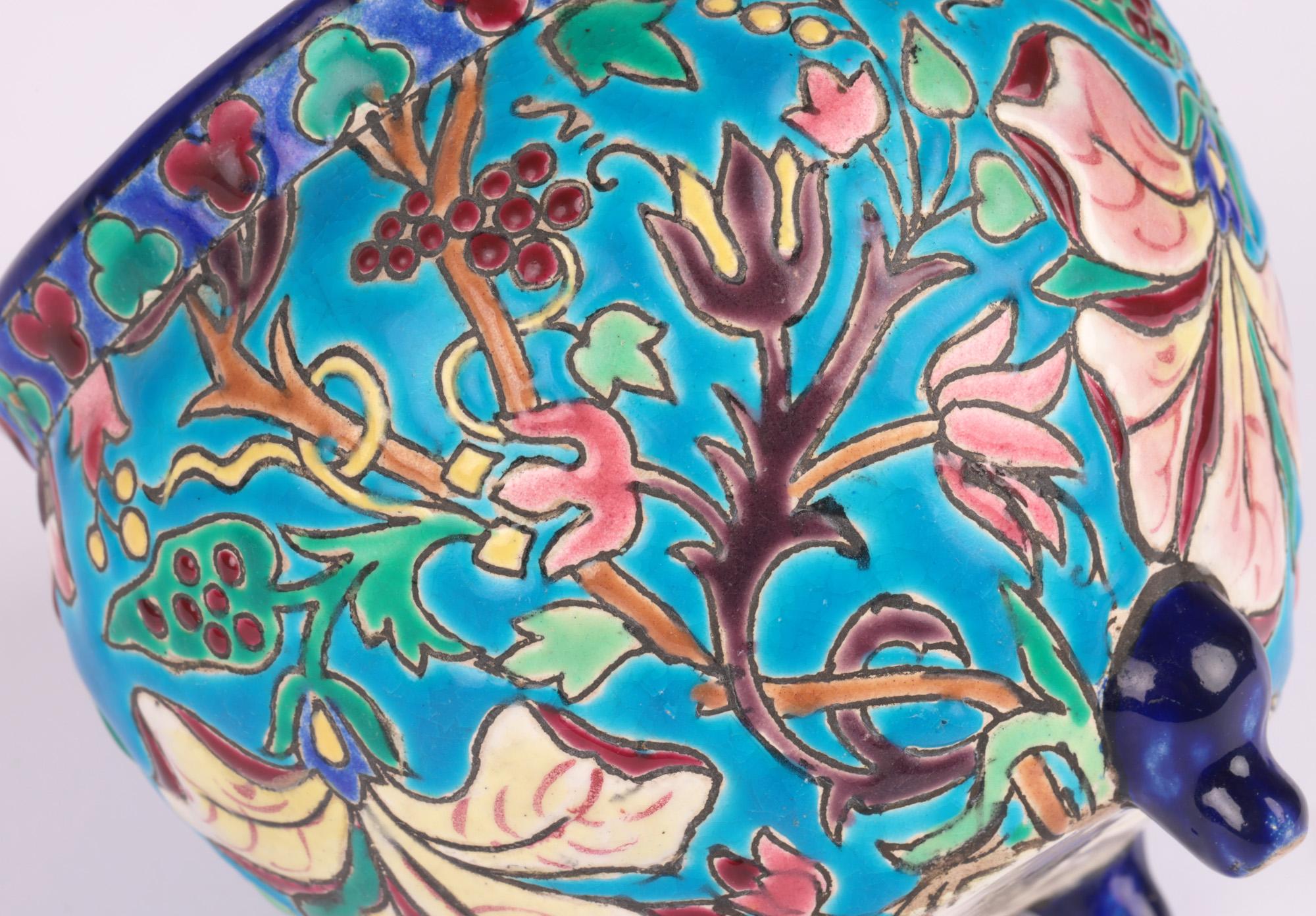 Fine French Art Deco pottery majolica glazed art pottery vase decorated with floral designs by Longwy and dating from around 1920. The earthenware vase stands raised on three small scroll legs with a wide round urn shaped body and is extensively