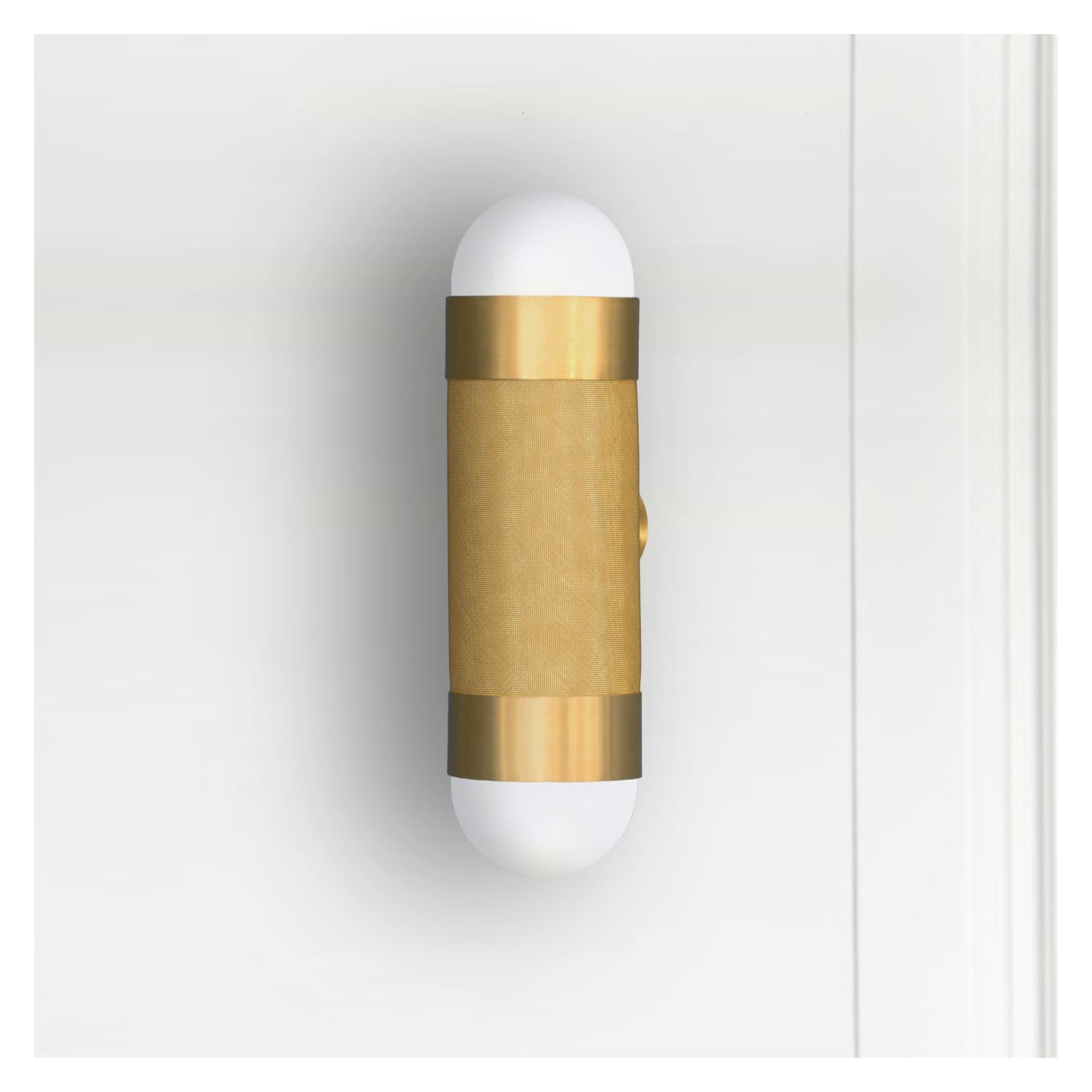 The Loom wall light is defined by its signature woven brass cylinder topped with hand-brushed brass sleeves and completed with soft-white borosilicate glass domes. When illuminated the LOOM emanates a soft, warm glow through the brass weave,