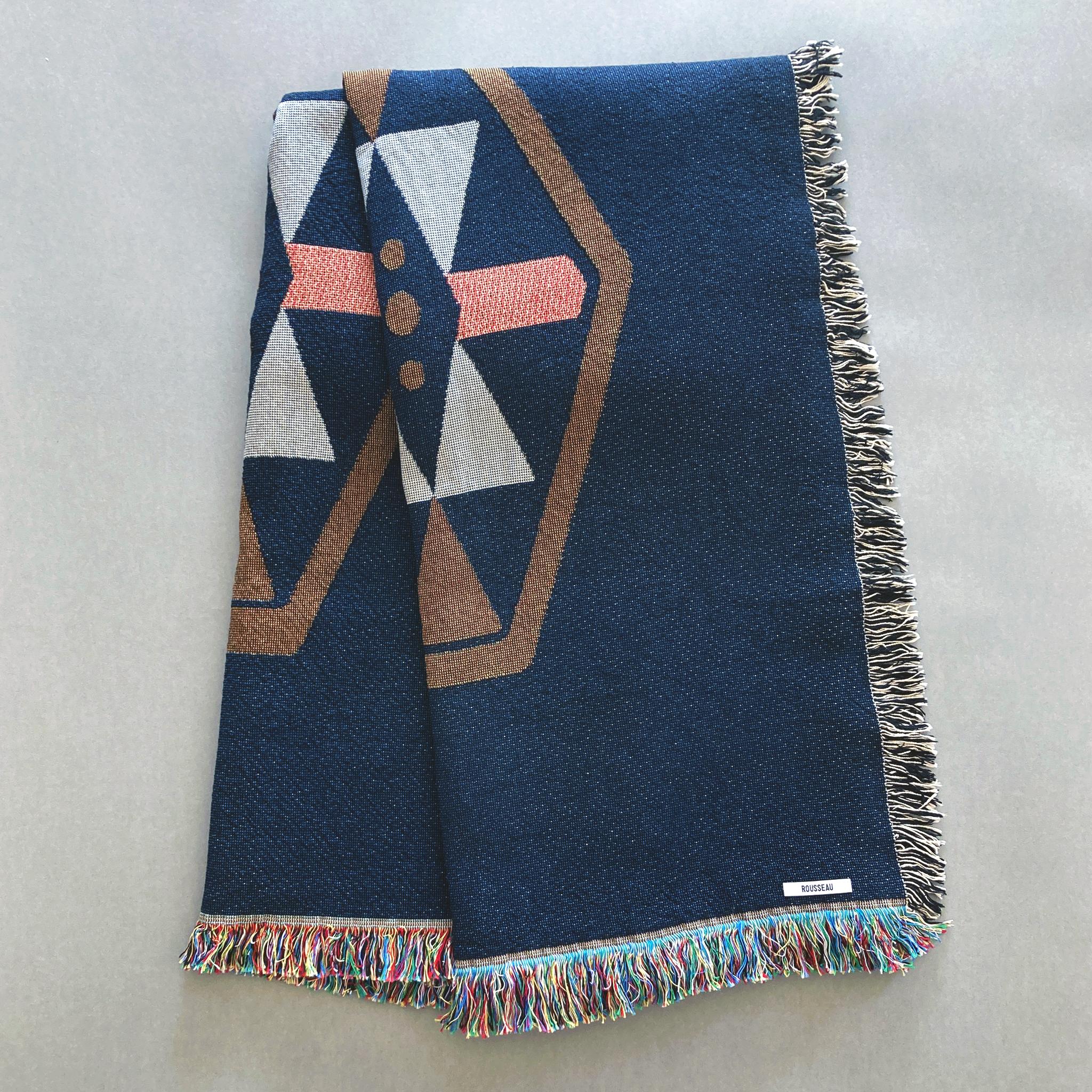 Twilight navy geo woven throw with fringe edge. Accent colors are pink, ochre, gray. Woven with recycled cotton on a jacquard loom, made in the US. Each throw measures 54 x 72 inches.

The geometric patterned throw is inspired by a hand embroidered