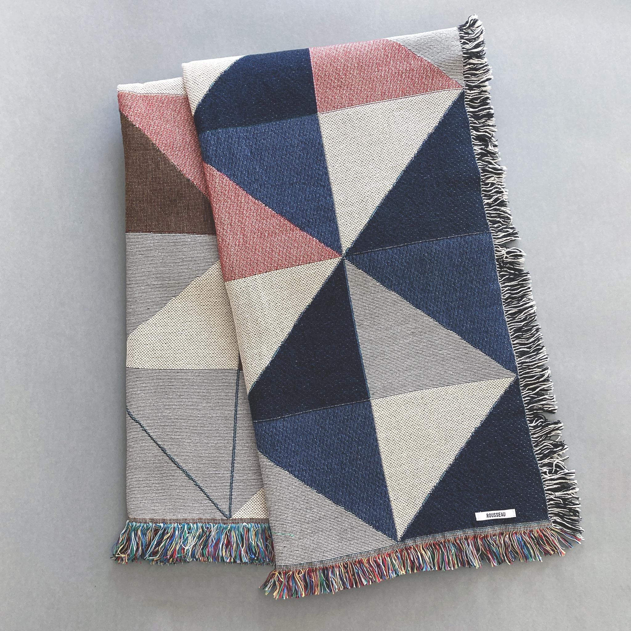 The Sixteen throw in navy, pink, ochre and gray geometric print woven throw with fringe edge. Woven with recycled cotton on a jacquard loom, made in the US. Each throw measures 54 x 72 inches.

This geometric patterned throw is inspired by a
