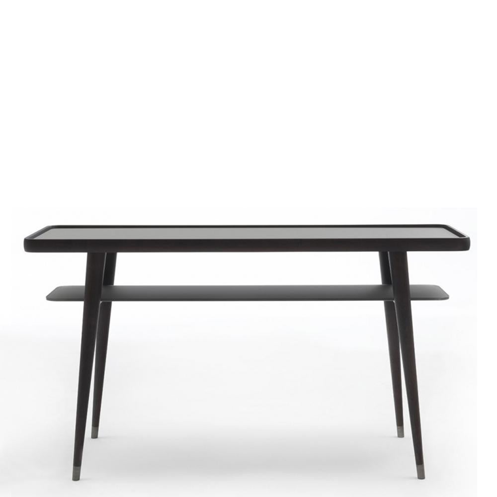 Consola Looman con estructura de madera maciza de fresno
y con 1 estante de cristal smocked bajo la parte superior. Consola
con pies extremos de metal cepillado.
También disponible a petición en:
Madera maciza de fresno teñida en Mooka con 1 estante