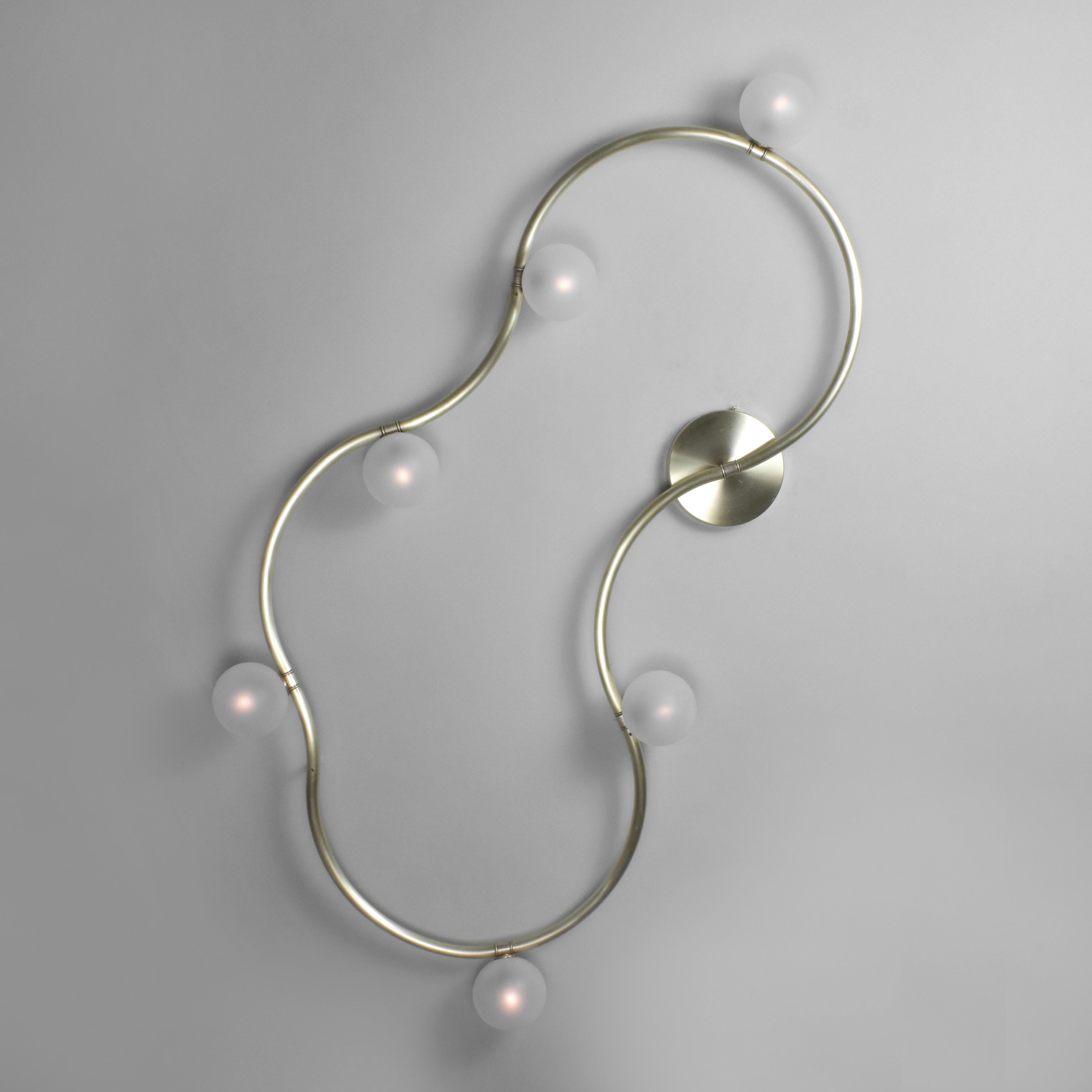 Modular Lighting designed and produced by Talbot & Yoon.

The Loop Light uses a bent brass tube and diamond tiling pattern composed of two unique shapes to create an endless variety of looped and squiggly wall sconces. 

The Loop Light is