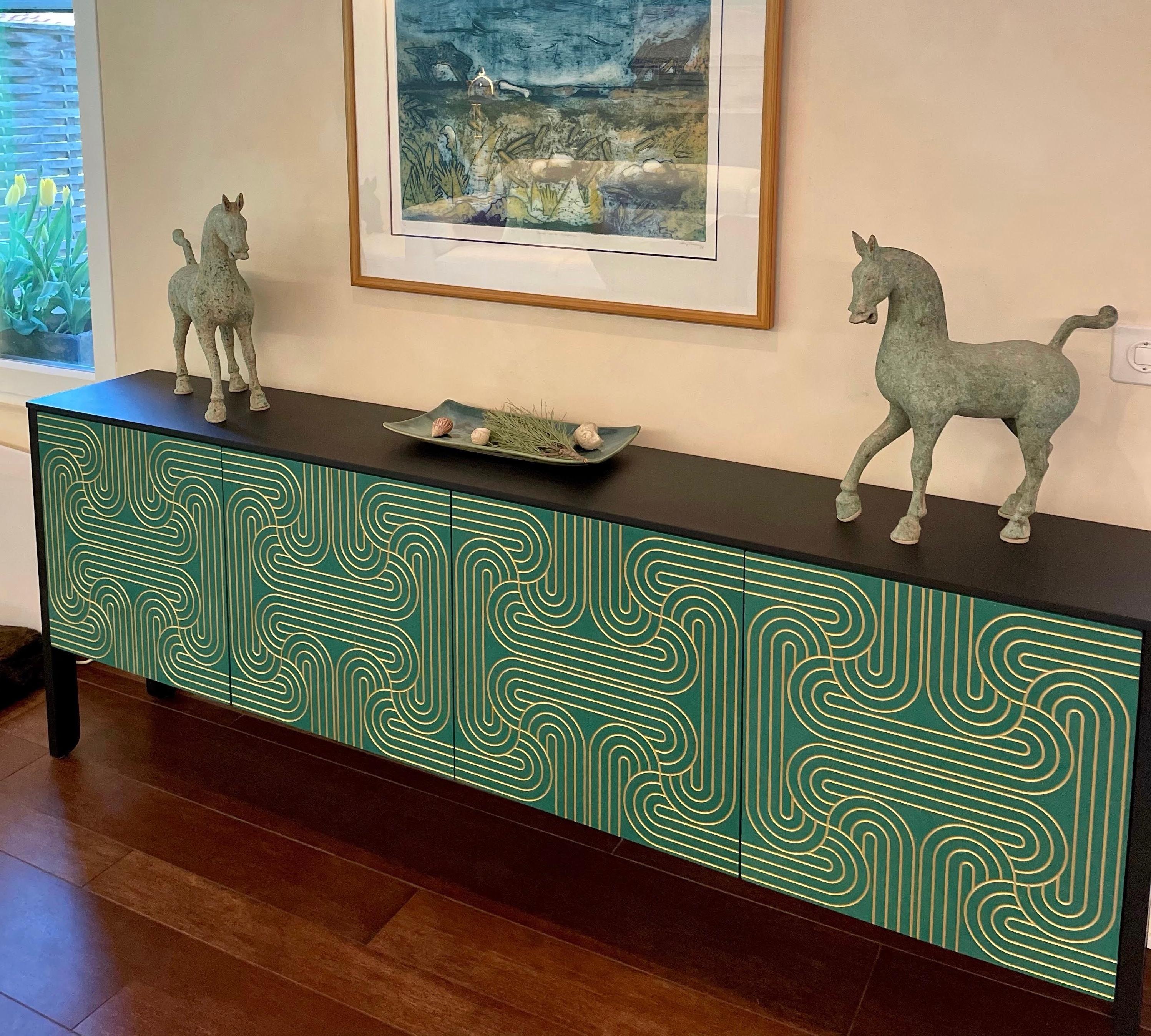 The stunning Loop Sideboards are available in a range of colours, verdant Green, bold Blue or striking Black.
The elegant Loop pattern is engraved onto the doors and handpainted in gold.
Each piece is finished by hand using a environmentally