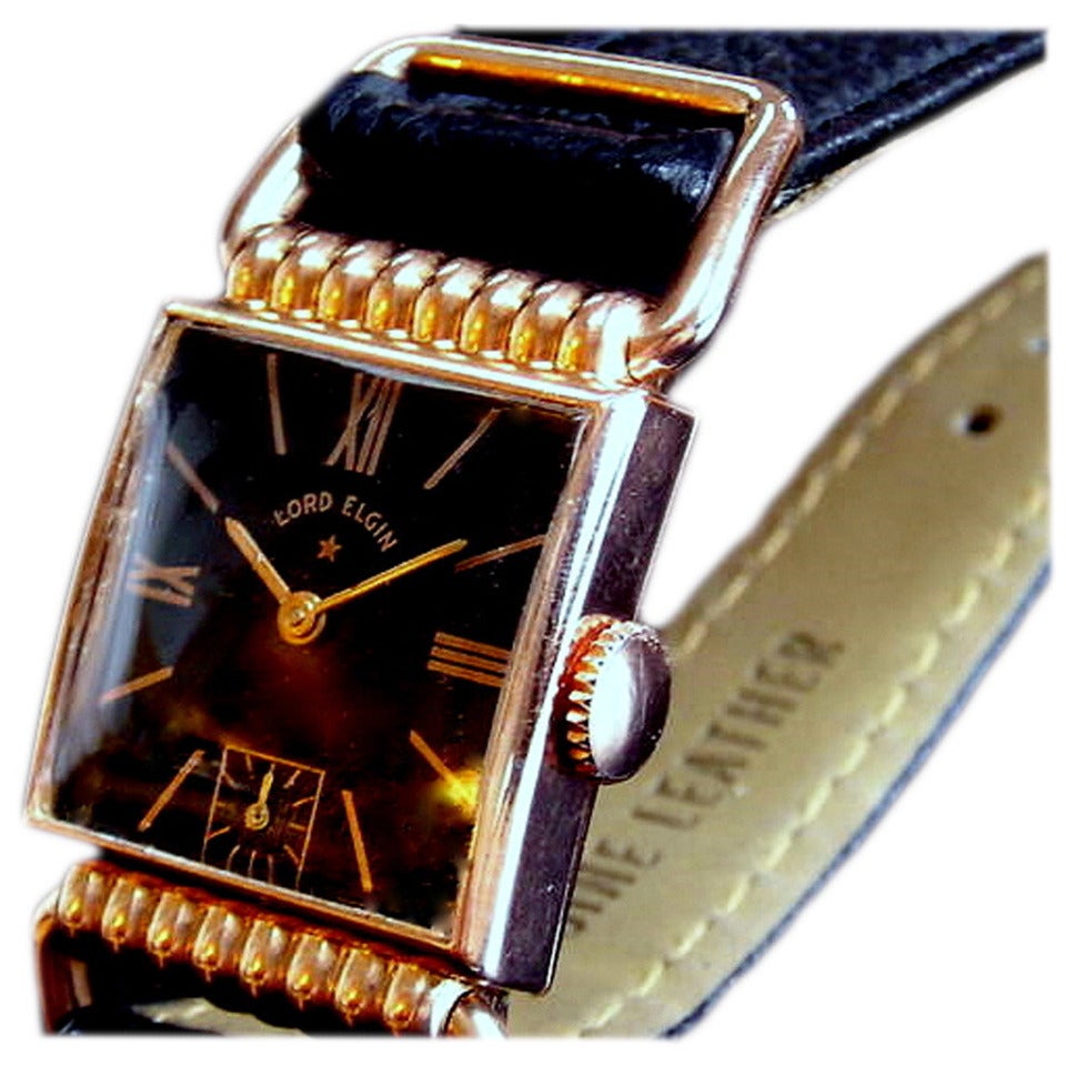 The dial on this watch is in excellent condition. It is Black with small, shiny gold studs all the way around the outer edge for minute markers and raised gold Art Deco, Arabic numbers at the hour points. The six-position has a square Sub-second
