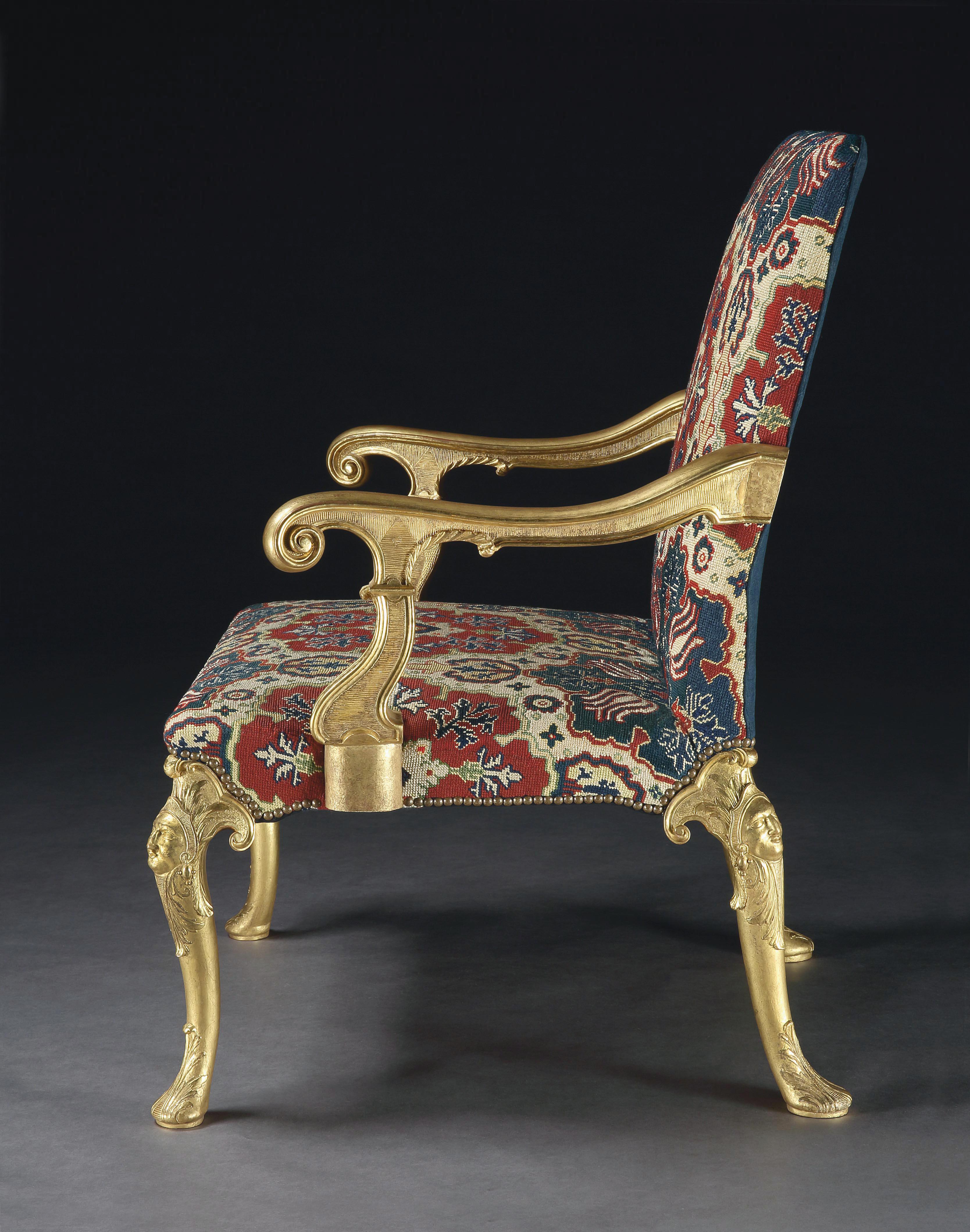 An exceptional, Important and well documented pair of George I Gilt gesso open armchairs. Covered in their original blue and red wool and silk needlework. The pronounced scrolled arms above acanthus carved supports, all standing on cabriole legs