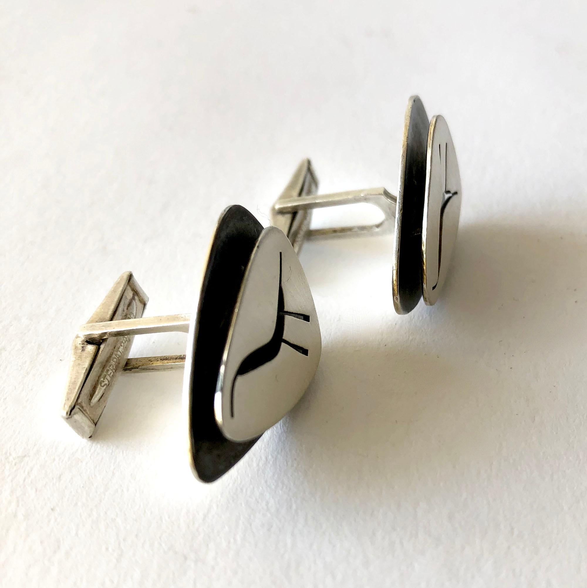 Double layered sterling silver cufflinks with pierced design of a modernist bird created by Lore Garrick of New York City, circa 1960's. Cufflinks measure 1 1/8