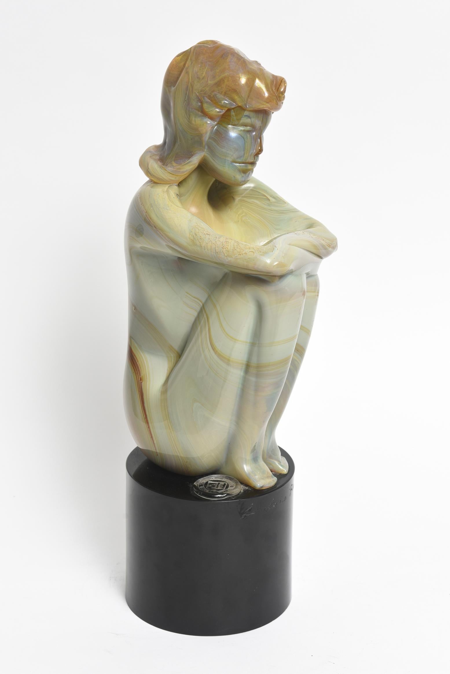 Loredano Rosin (Italian 1936-1992)
Beautiful Murano glass sculpture of a female nude seated or kneeling with shoulder length hair and her arms crossed over her legs. The type of glass is called calcedonia resulting in tones of yellow, green, blue