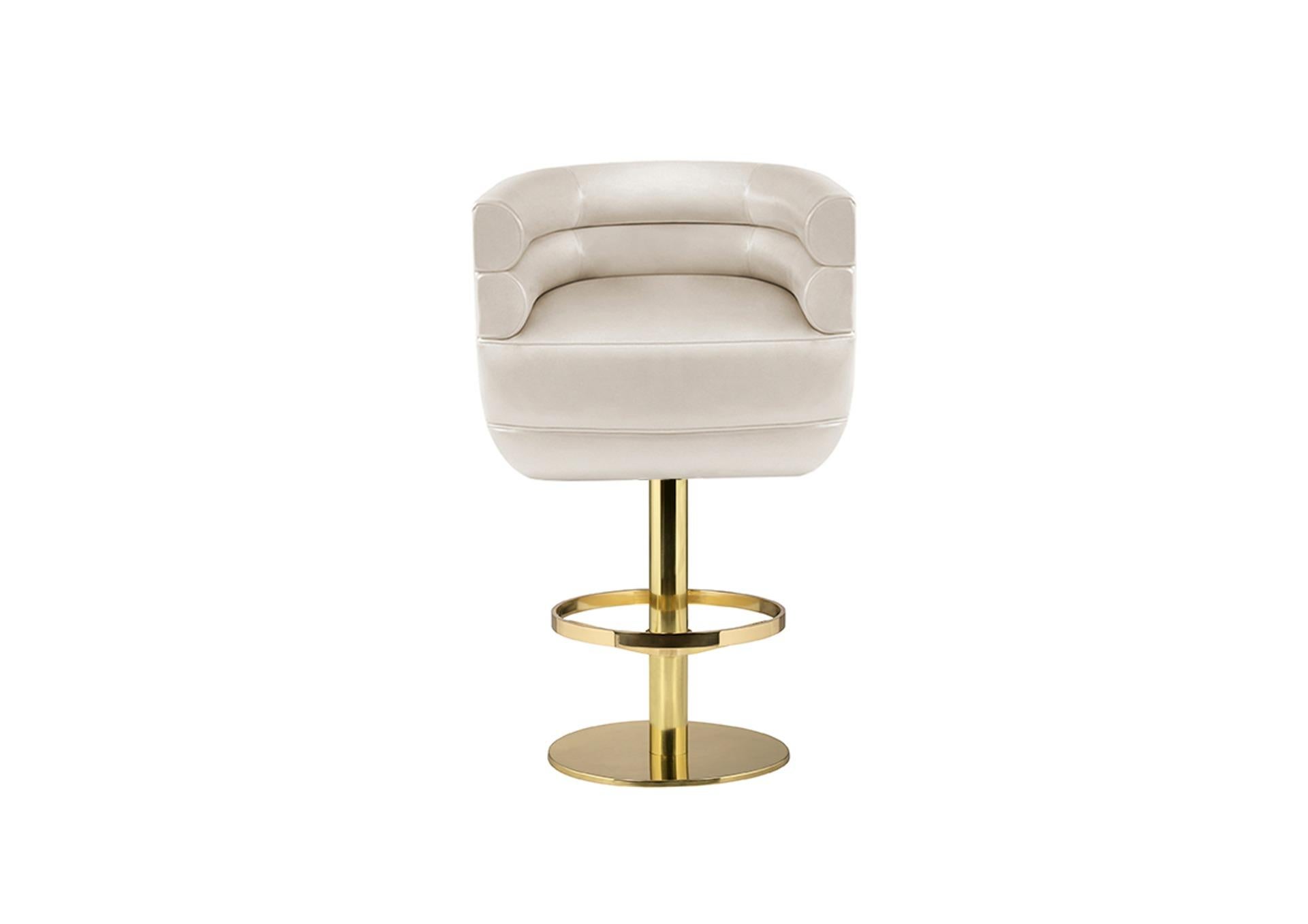 Inspired in the mid-century design but with a contemporary look, Loren is a posh accent bar chair with sinuous curves on its back. Supported by a round polished brass base and a footrest for comfort, Loren is upholstered in a creamy leather and a