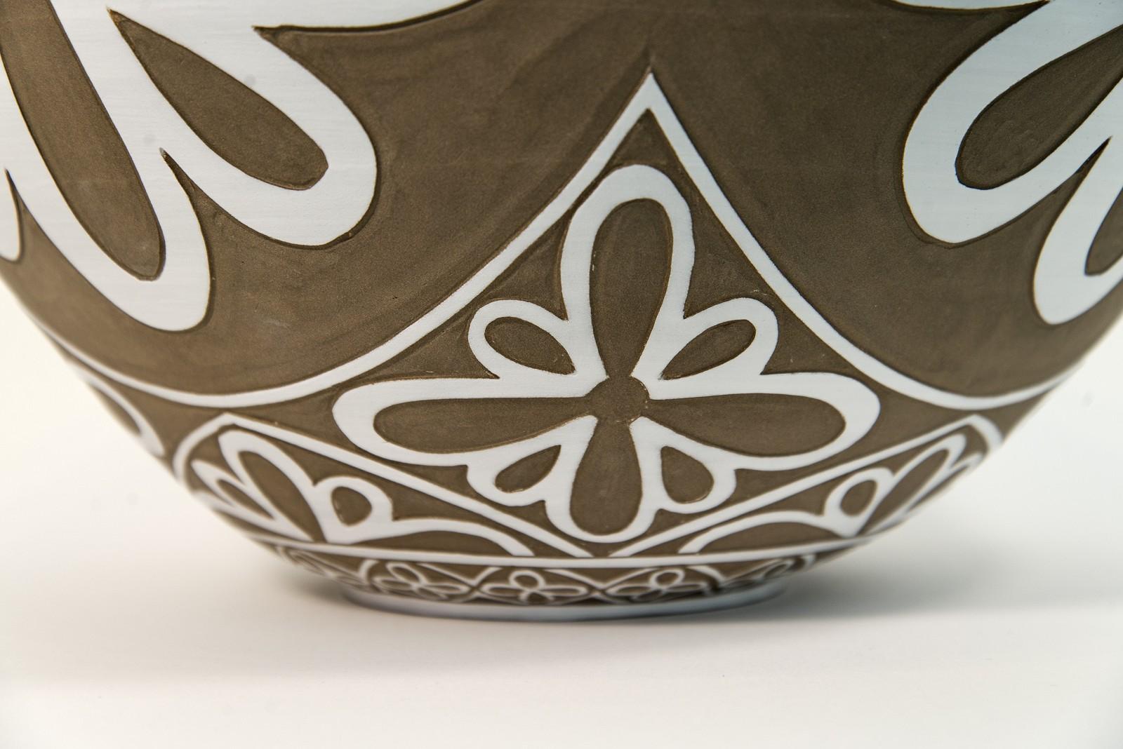 Dieses taupefarbene Porzellangefäß von Loren Kaplan ziert ein feines, von Hand graviertes weißes Blumenmuster. Die klassische Form und die Details erinnern an antike Gefäße. Kaplans Arbeiten sind sehr strukturiert und zum Anfassen gedacht. 

