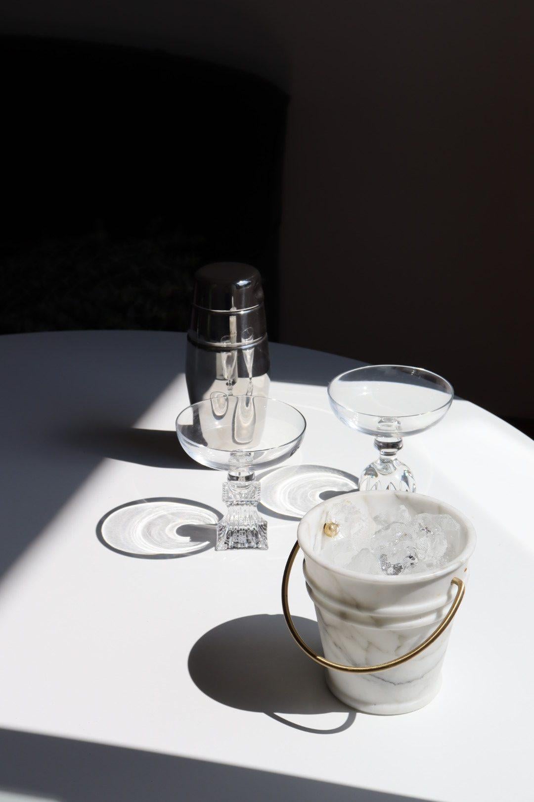 Vaso a secchiello fatto a mano in marmo Arabescato di Lorenza Bozzoli, Editions Milano, Italia. Secchio in marmo Arabescato opaco con manico in ottone spazzolato a mano. Ricorda il tradizionale secchio di zinco grazie all'utilizzo di un materiale