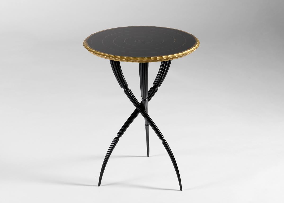 This elegant side table features a round top with a scalloped edge and rests upon three intertwining legs that taper dramatically as they descend to the floor. With it, the artist has assembled forms which do not merely intimate motion, but draw the