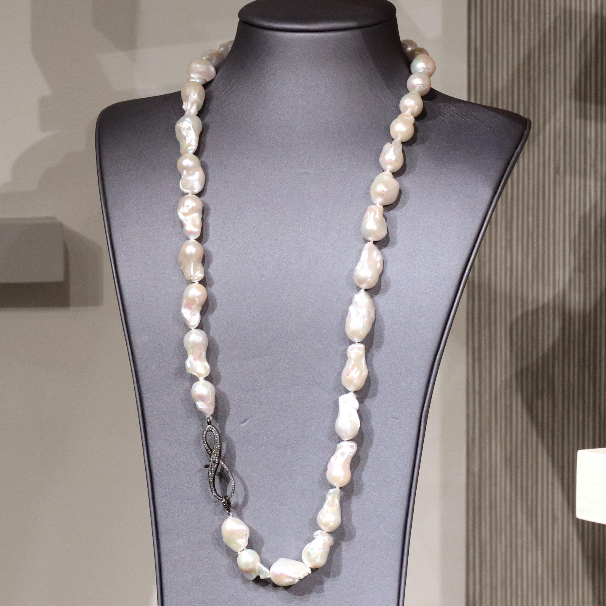 Long Freshwater Pearl Necklace by jewelry designer Lori Barros featuring a gorgeous strand of wonderfully-iridescent white freshwater baroque pearls and finished with a two inch long pave' diamond encrusted jumbo infinity-shaped ornamental clasp