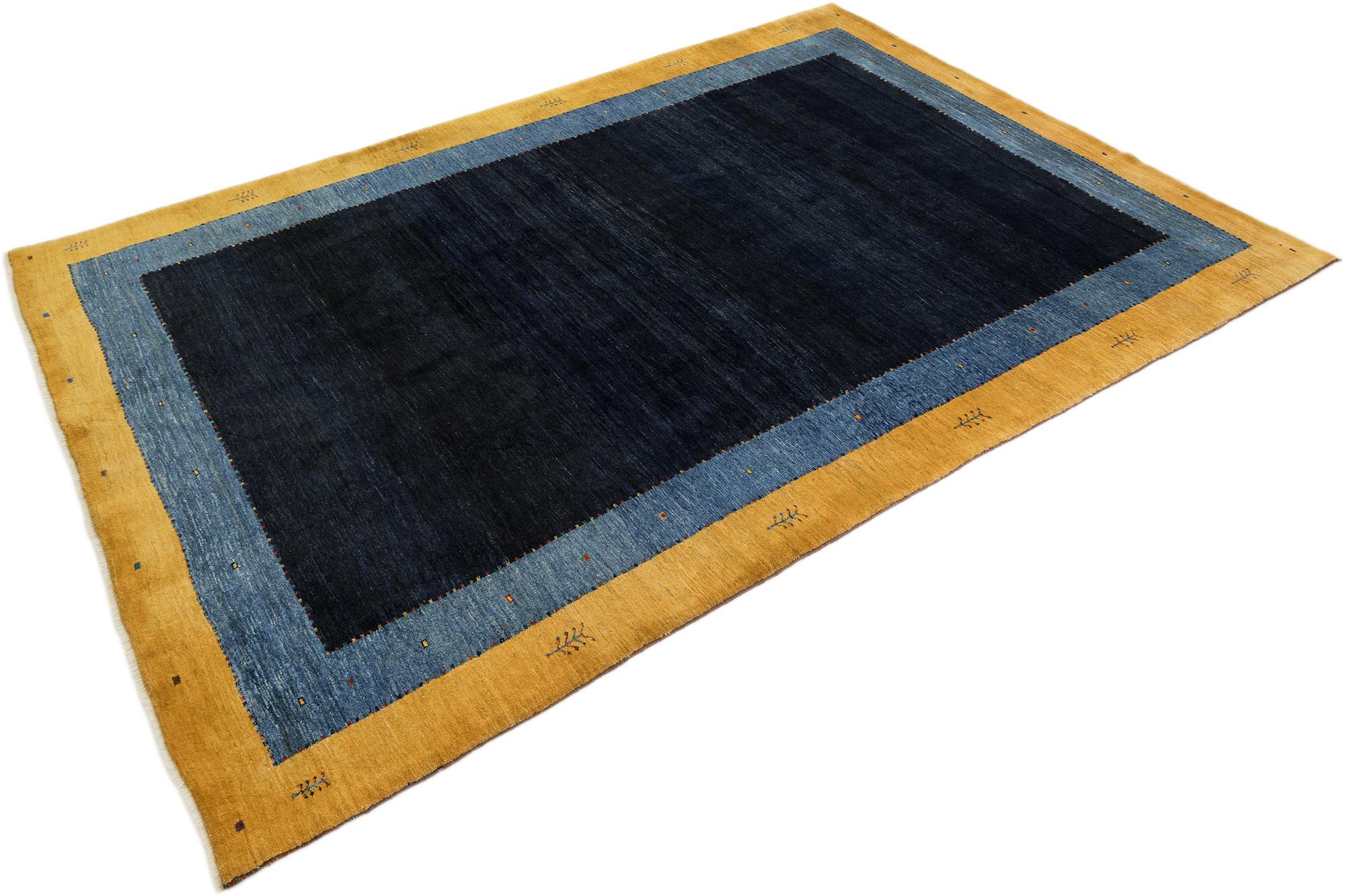 Handgeknüpfter Lori Gabbeh-Teppich, gewebt von Stammeswebern im Iran.

Dieses minimalistische Stück hebt die Gabbeh-Tradition mit einem kühnen offenen Feld in tiefem Indigoblau hervor, das von einer breiten blauen und goldenen Bordüre eingerahmt
