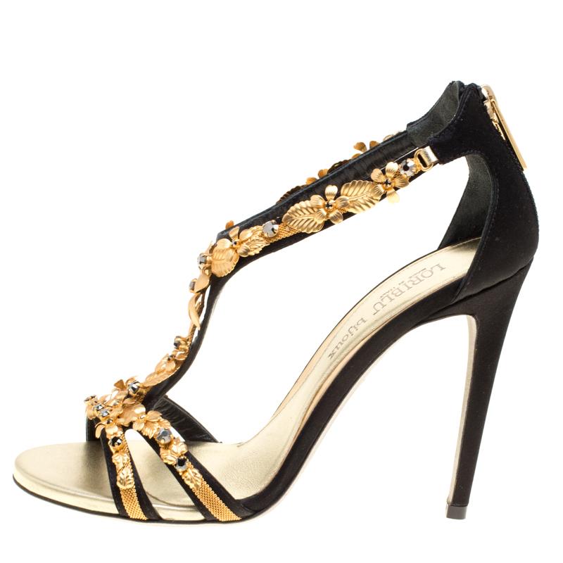 The intriguing gold-tone, floral embellishments that adorn the front straps and beautifully extend to the T-strap finishing just before the counters, make these black satin sandals from Loriblu Bijoux a statement piece worth-possessing. The pair has