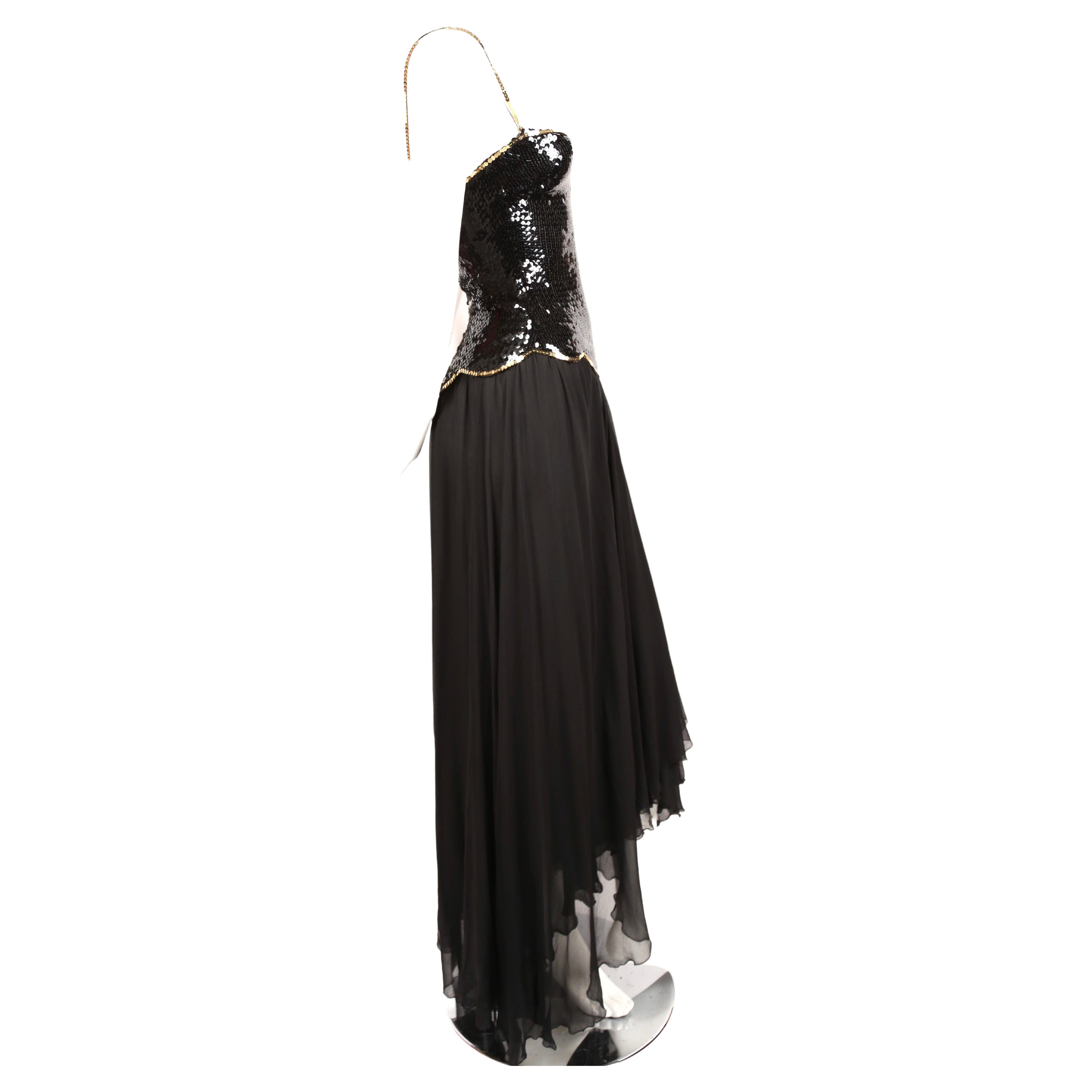 Jet-black sequined gown with gold trim and silk mousseline skirt designed by Loris Azzaro dating to the late 1970's. Labeled a size 6 however this best fits a US 2. Measures approximately 32