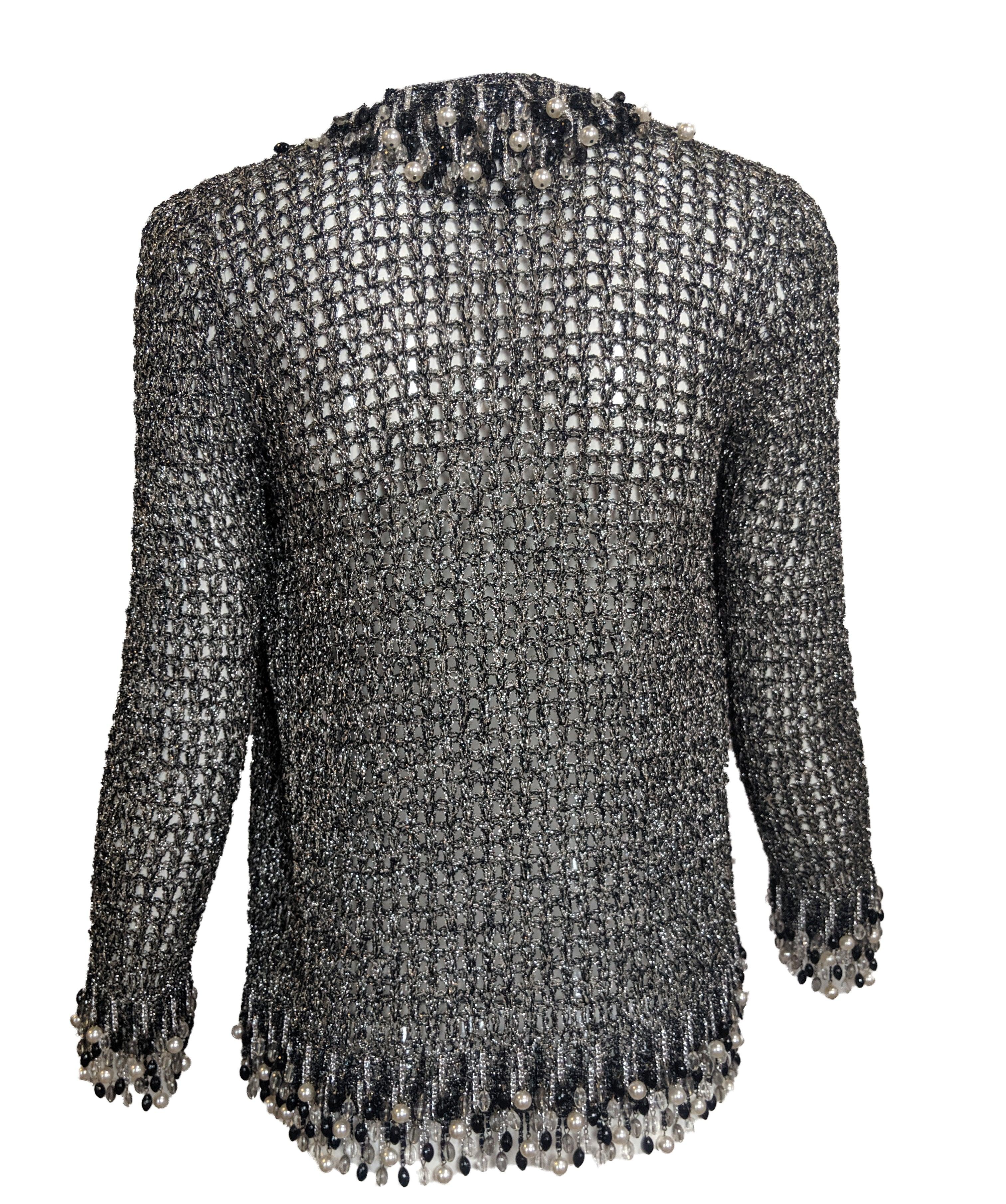 This fabulous piece has an obvious attribution to iconic designer Loris Azzaro, circa 1970s. Black and silver crochet cardigan with snap closure. Dangling fringe of black and silver-tone chain with crystals and faux pearls. Makes a lovely tinkling