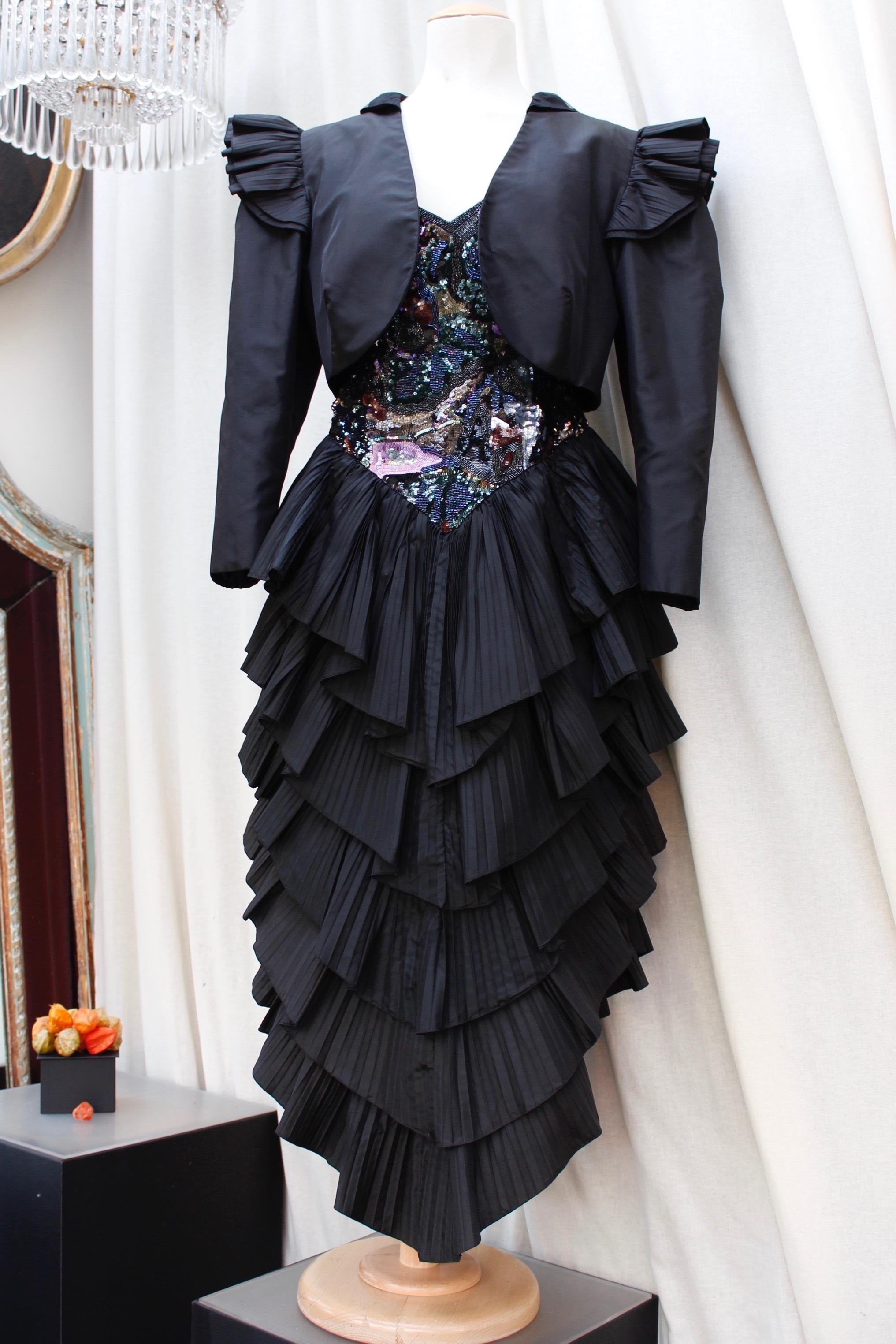 LORIS AZZARO PARIS (Made in France) Beautiful black taffeta evening comprised of a bolero and a halter dress. The jacket is decorated at the shoulders with two rows of pleated flounces. It closes with three hooks.
The bustier is entirely embroidered