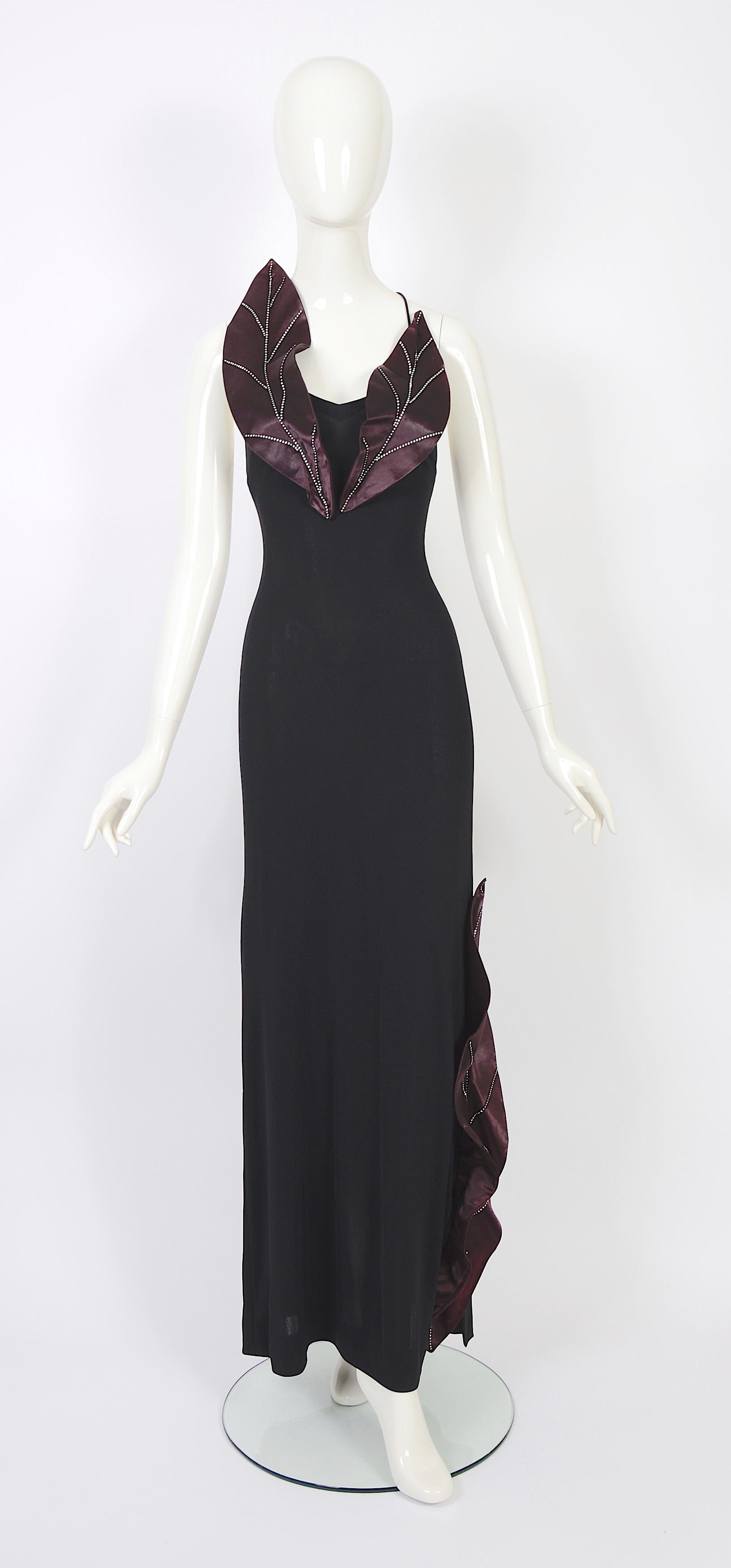Verlaine Vintage is thrilled to present an exquisite 1970s open-back vintage dress by Loris Azzaro.
Crafted from a luxuriously soft black silk and viscose mix jersey fabric, this dress features attached embellished satin & diamante leaves that add a