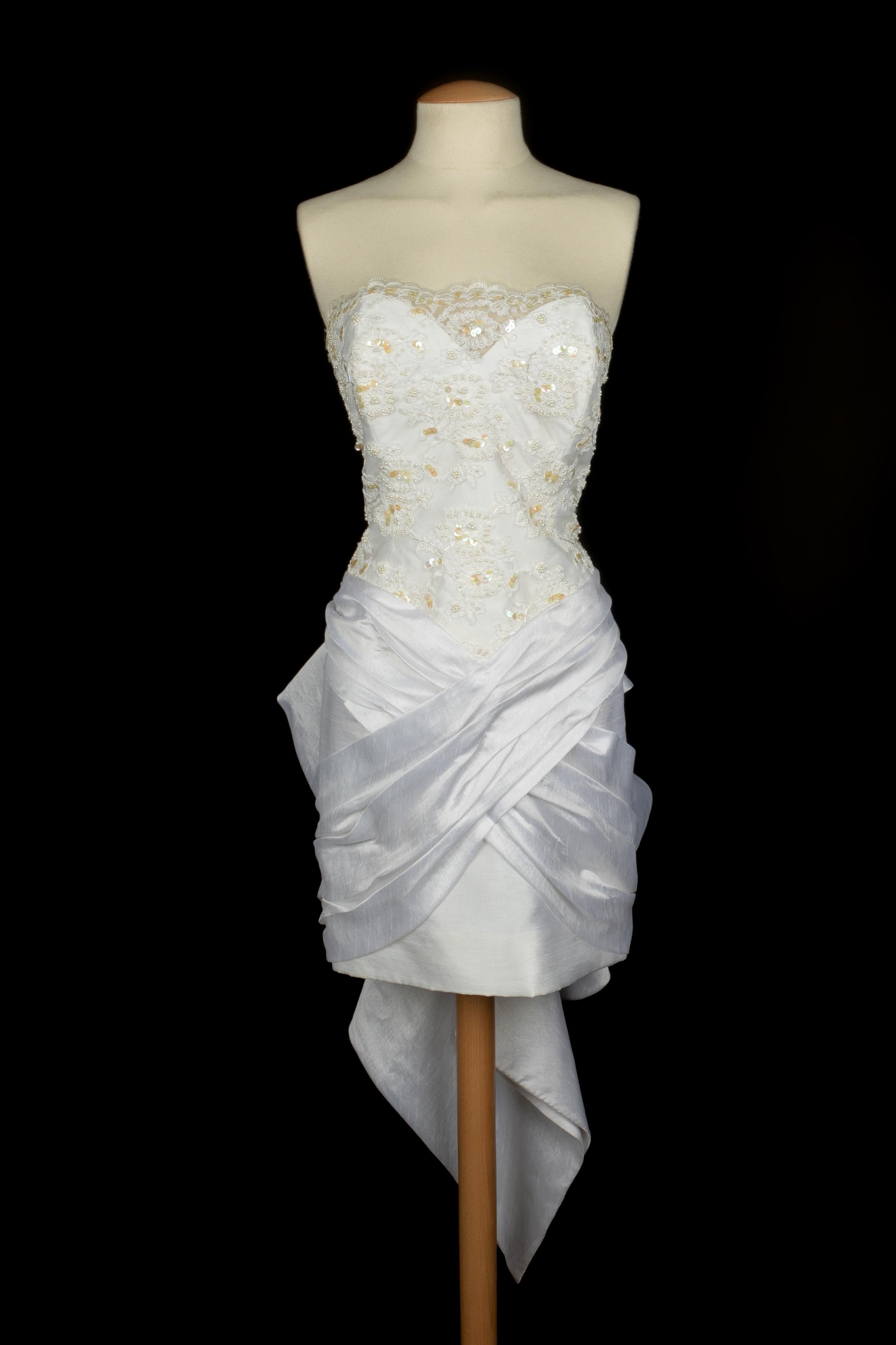 LORIS AZZARO - (Fabriquée en France) Robe courte bustier en dentelle brodée de perles et de paillettes. Le bas de la robe est en soie blanche. Aucune taille n'est indiquée, il convient à un 40FR/42FR.

Condit :
Très bon état.

Dimensions :
Poitrine