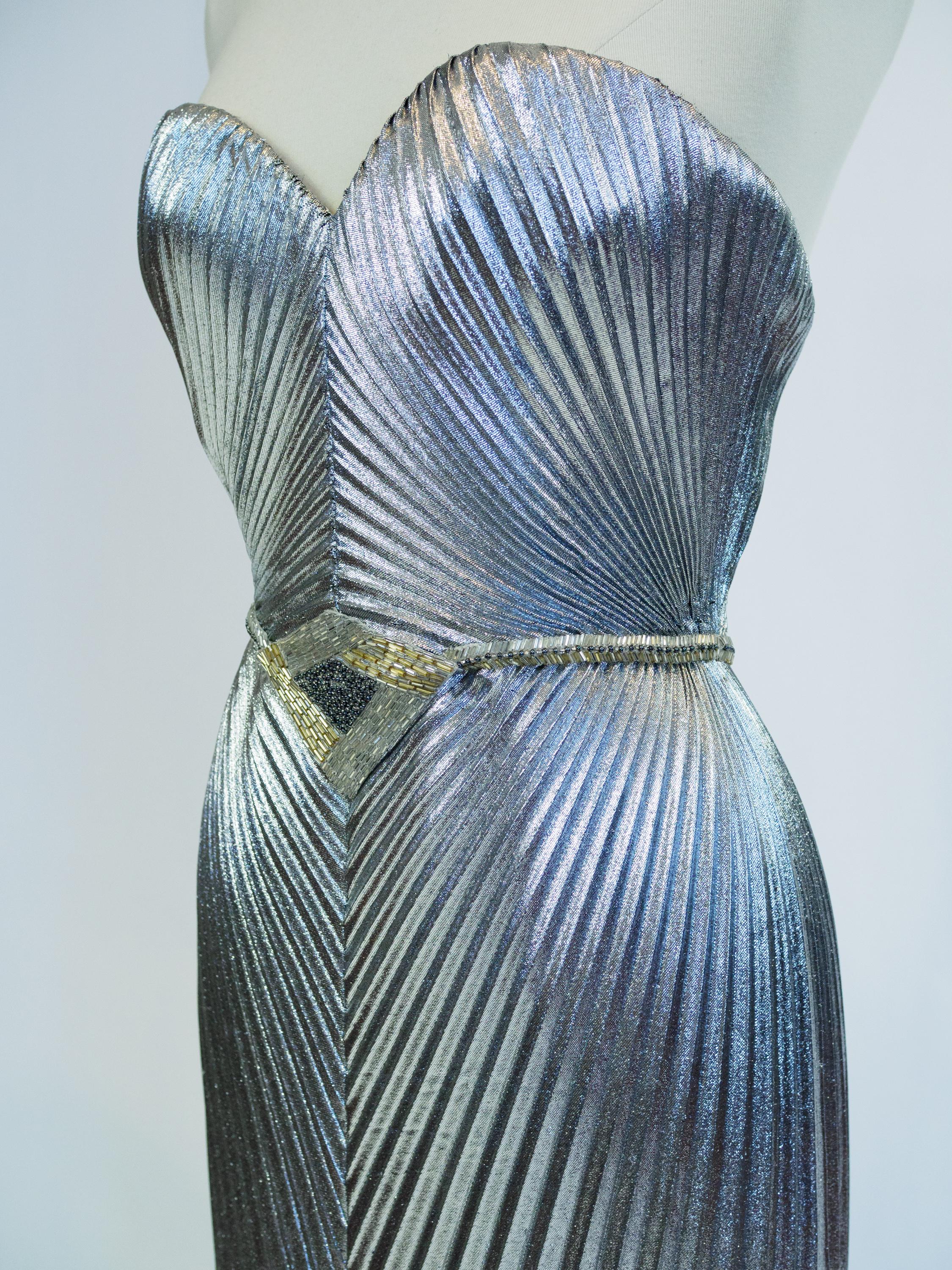 Circa 1980

France

Impressive evening dress in sun pleats and silver lamé by Loris Azzaro Haute Couture from the 1980s. Bodycon dress with large open back neckline and zipper in the back. Internal boned bustier with integrated bra with padded cups.