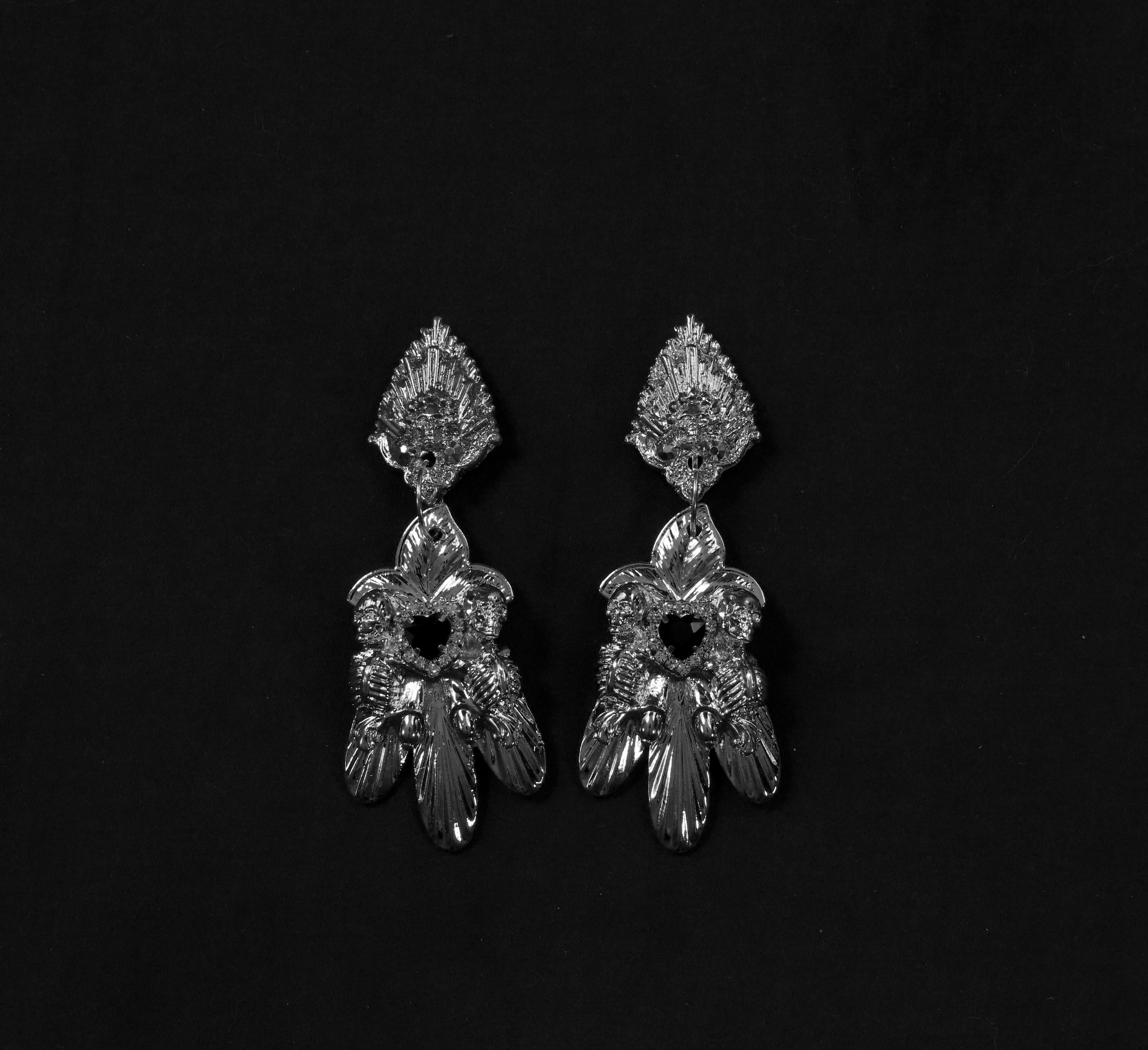 Lorna Earrings by Angelis Blade

A delicate fusion of beauty and remembrance, the Lorna Earrings embody femininity with a shadowed edge. This floral drop design is graced by two skeletal figures, gently embracing a faceted glass heart gemstone—a