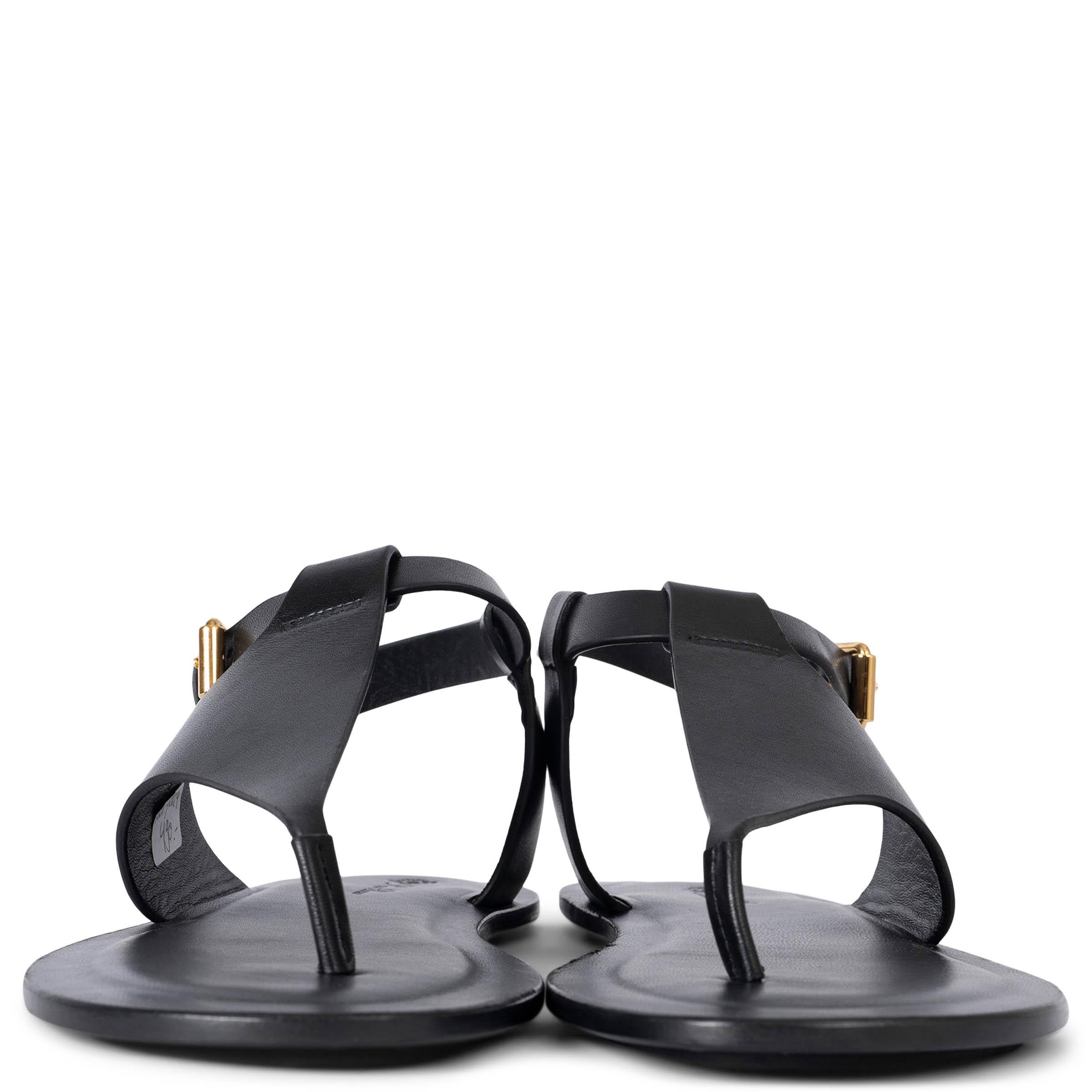 These 100% authentic Loro Piana Trani thong sandals are crafted from black semi-glossy, super soft leather, offering a luxurious feel and sleek design. They feature an elegant ankle strap with a gold-tone metal buckle and are finished with leather