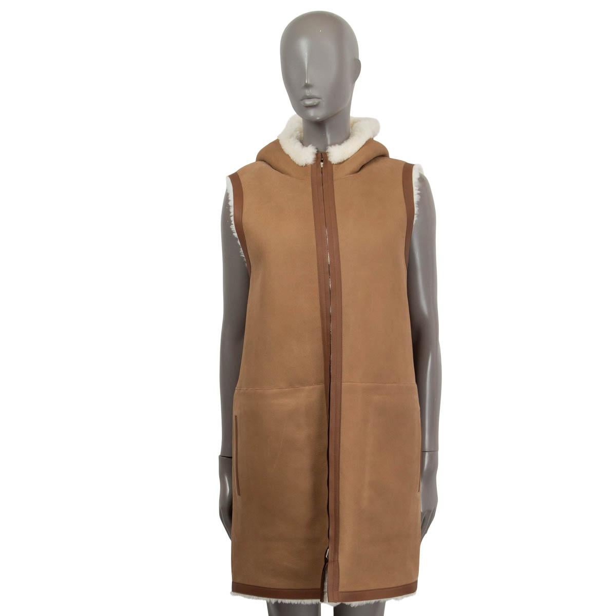100% authentic Loro Piana 'Henry' reversible hooded shearling vest in pale camel and off-white dyed lamb fur (100%). Features two flap patch pockets on the shearling side and two slit pockets on the leather side. Opens with a double zipper on the