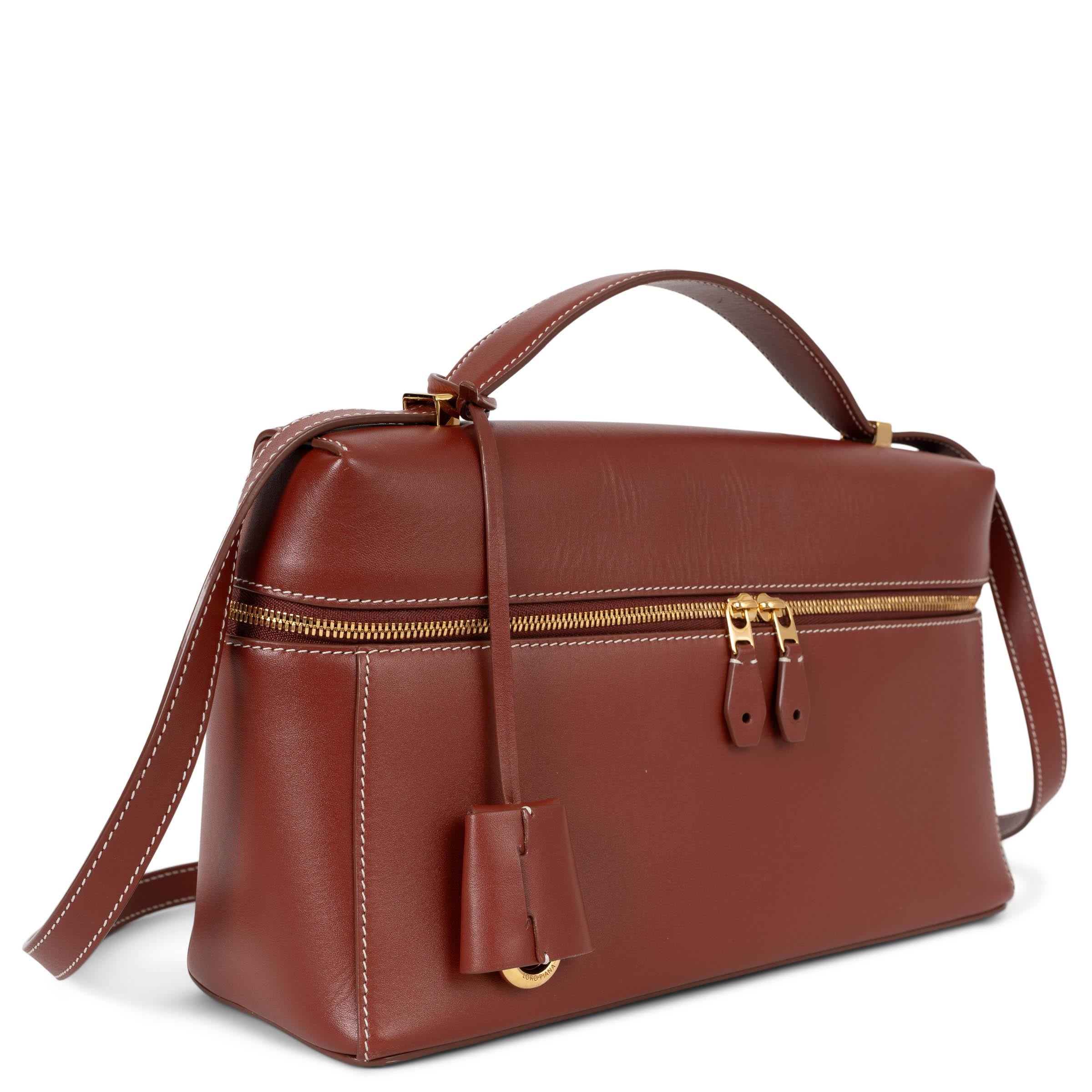 Ce sac L27 Extra 100% authentique de Loro Piana en cuir de veau lisse Deep Kummel (brun brique) est l'expression raffinée d'un luxe discret. Agrémenté de ferrures dorées, il présente un design polyvalent qui peut se porter à l'épaule ou en