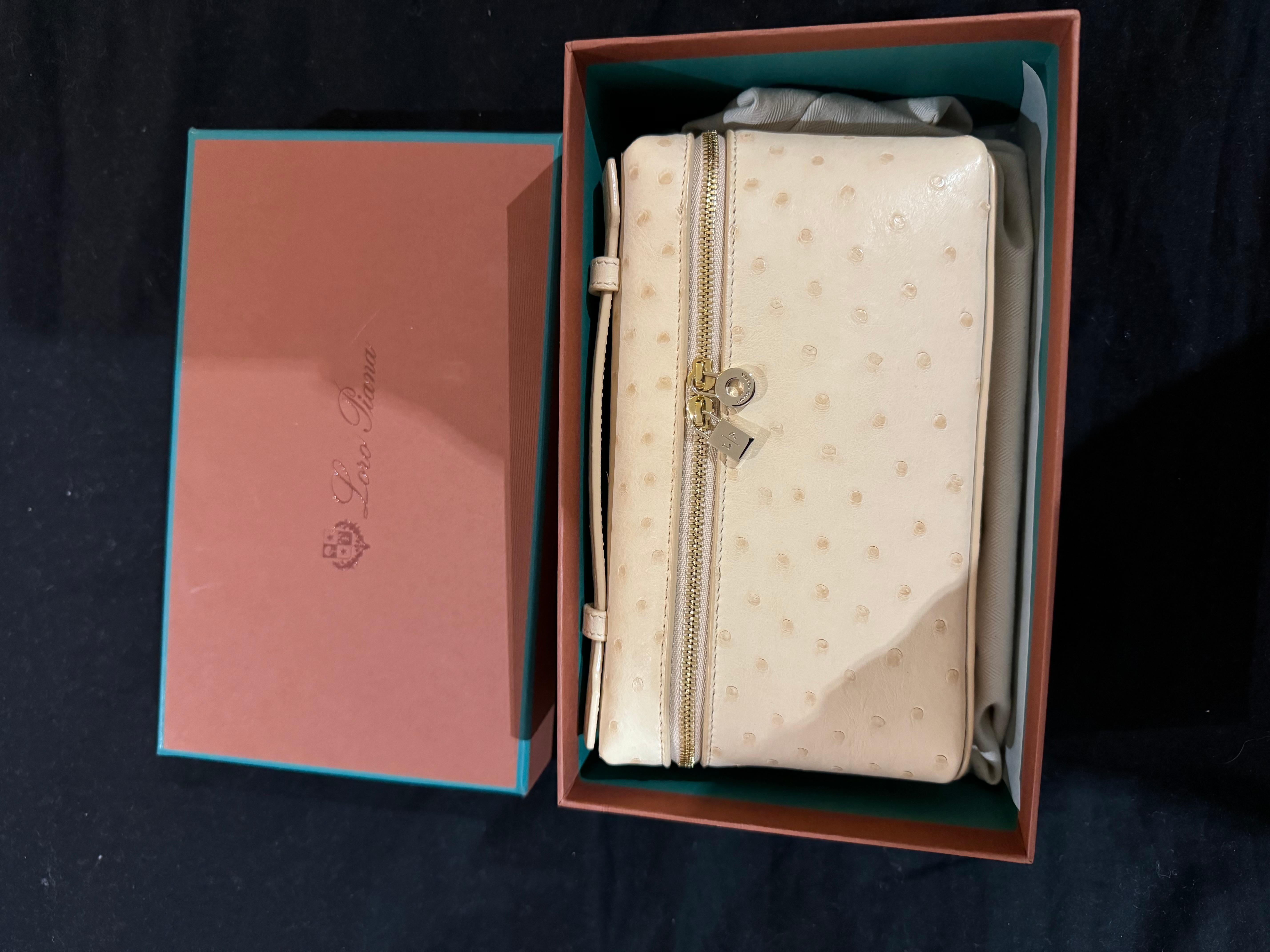 Loro Piana Extra Pocket Pouch L19 Bag in Ostrich leather in pink/beige colour with rose gold hardware. Loro Piana's pouch is elegant and versatile. The structured silhouette has been crafted from ostrich leather with a smooth finish and opens to a