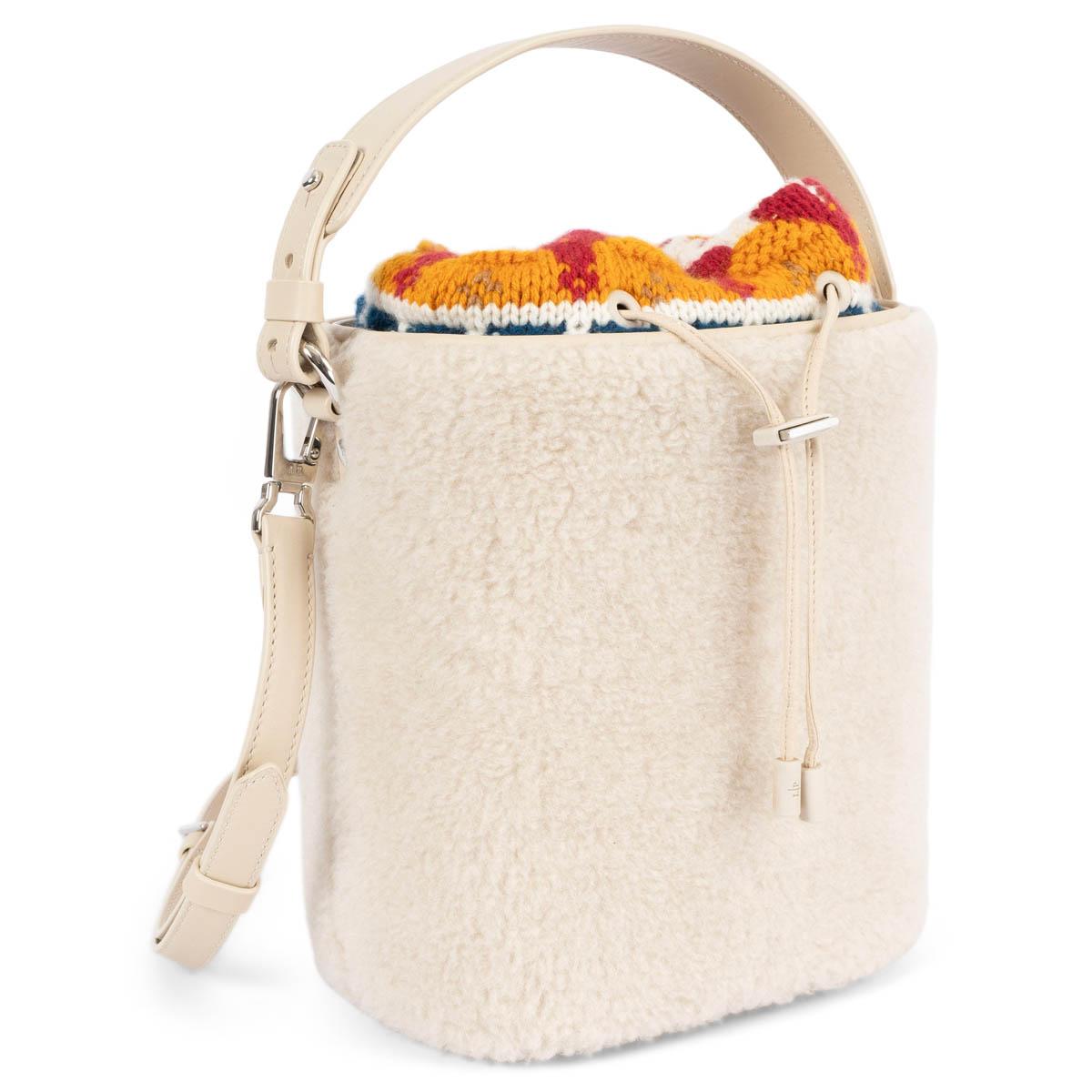 100% authentic Loro Piana Artemis bucket bag in ivory fluffy shearling with tonal leather trims. The design features an ivory, orange, red and blue knitted removable interior pouch, lined in smooth nappa leather with drawstring closure. The top