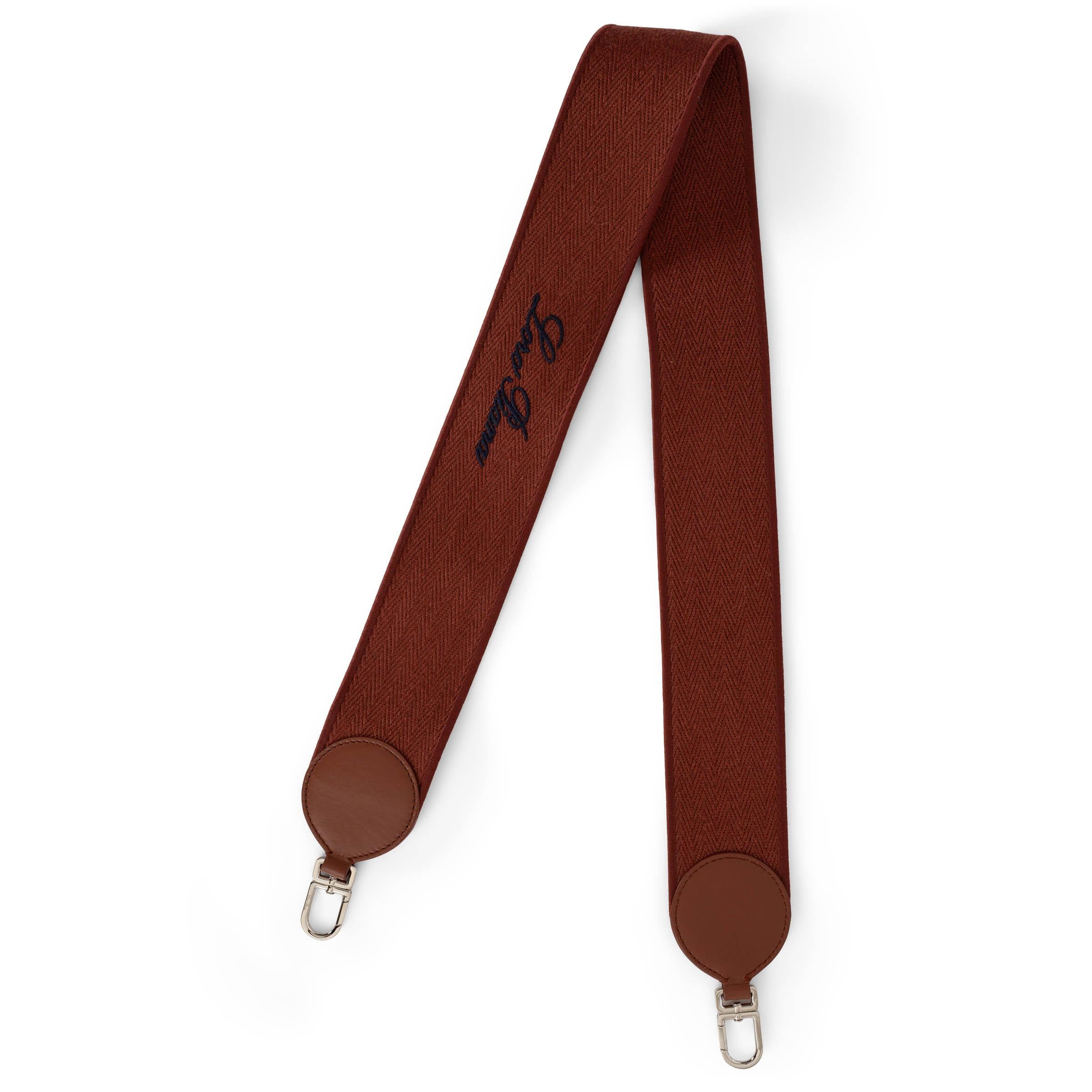 This 100% authentic Loro Piana Selvedge bag strap in Kummel (brick) canvas is a sophisticated accessory that enhances any bag with a touch of understated luxury. Featuring navy blue signature embroidery, brown leather trims, and silver-tone