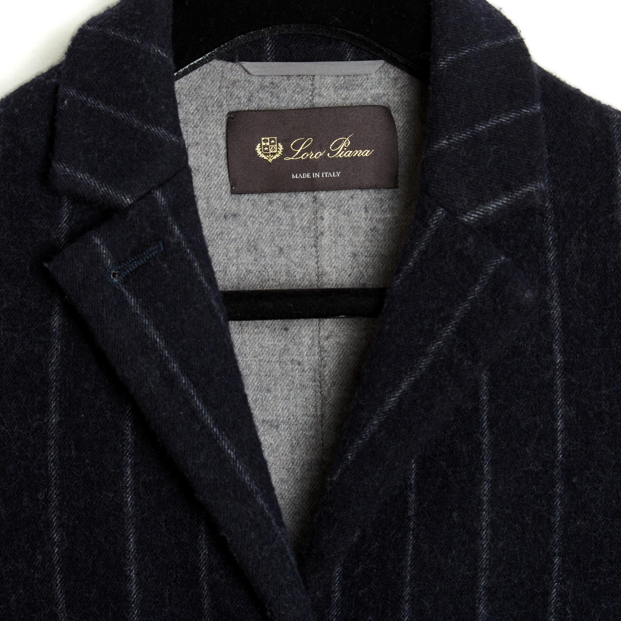Abrigo de lana Loro Piana de doble faz, gris antracita en el exterior y gris claro en el interior, cuello de muesca con tres botones ocultos, dos bolsillos con solapa a los lados, mangas largas forradas de seda con aberturas en el bajo y abertura en