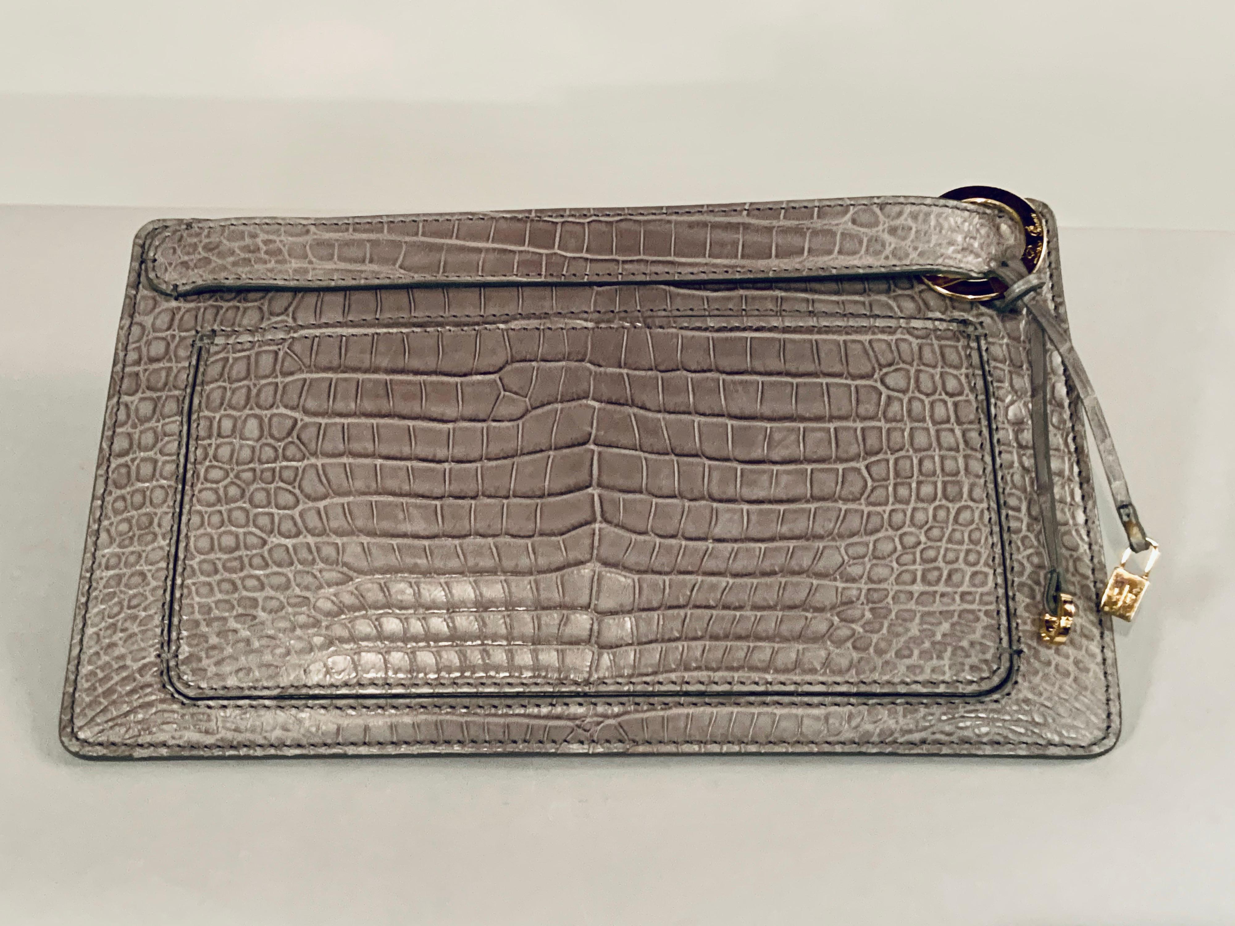Loro Piana has a reputation for the highest quality in material and workmanship and this bag is a perfect example.  Matte grey crocodile is used for this clutch with a concealed zip top and a front side slip pocket. There is a strap just above the