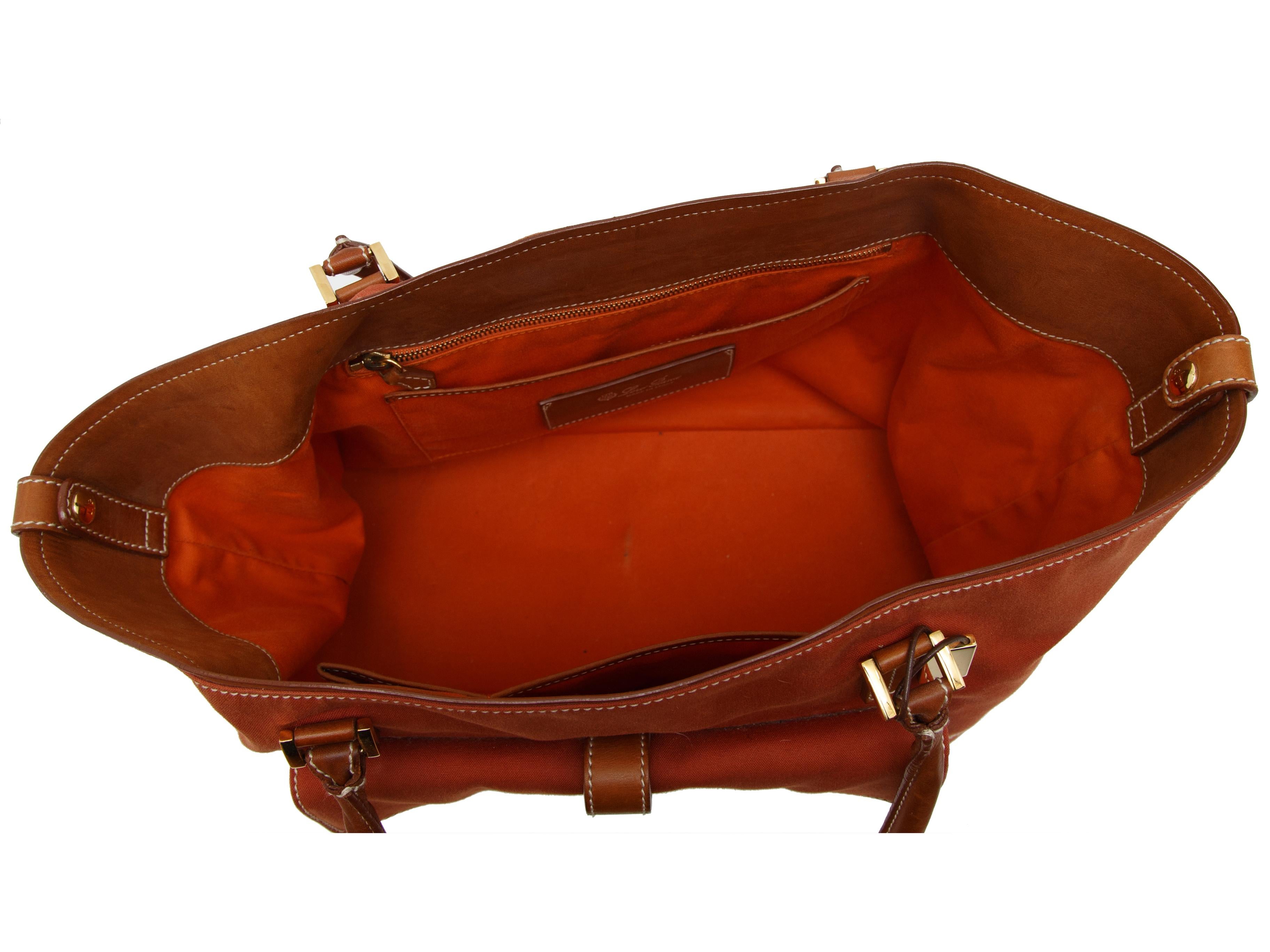 Product details: Orange leather-trimmed tote by Loro Piana. Contrast stitching throughout. Flap pocket at front. Zip pocket at back. 15