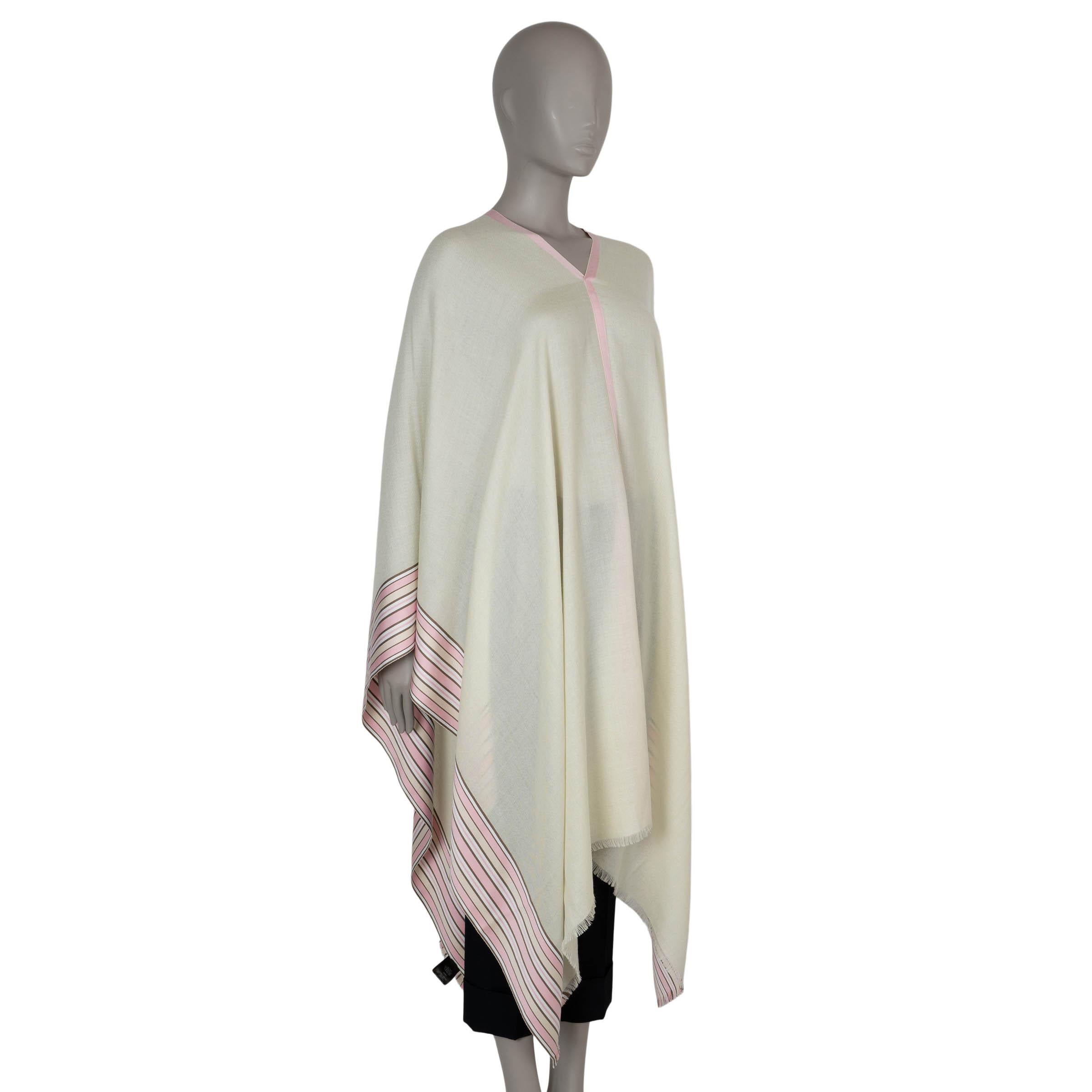 This 100% authentic Loro Piana poncho in vanilla silk (54%) and cashmere (46%) is a refined layering piece, showcasing the brand’s signature elegance. Adorned with suitcase stripes in pink, brown, and white, it features a V-neck and delicate fringed