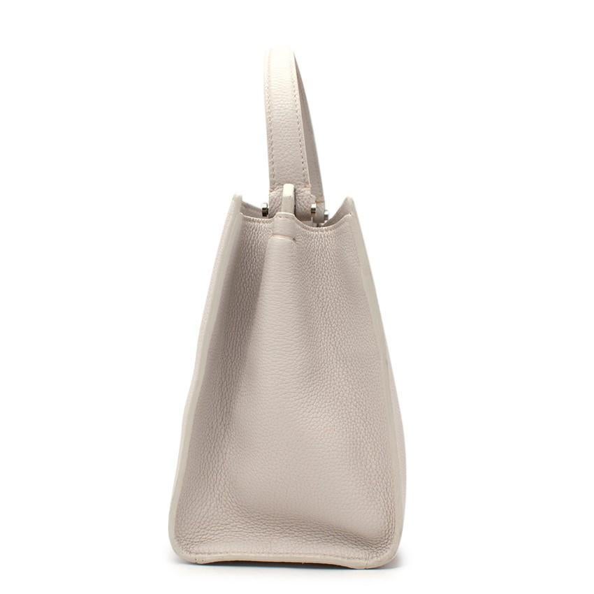 Loro Piana Pearl Grey Top Handle Bag

- Classic, rectangular grained leather top handle bag in a warm, pale peal grey hue
- 2 rolled leather top handles
- Minimal design, with single stud closure, and silver-tone metal hardware throughout
- Smooth