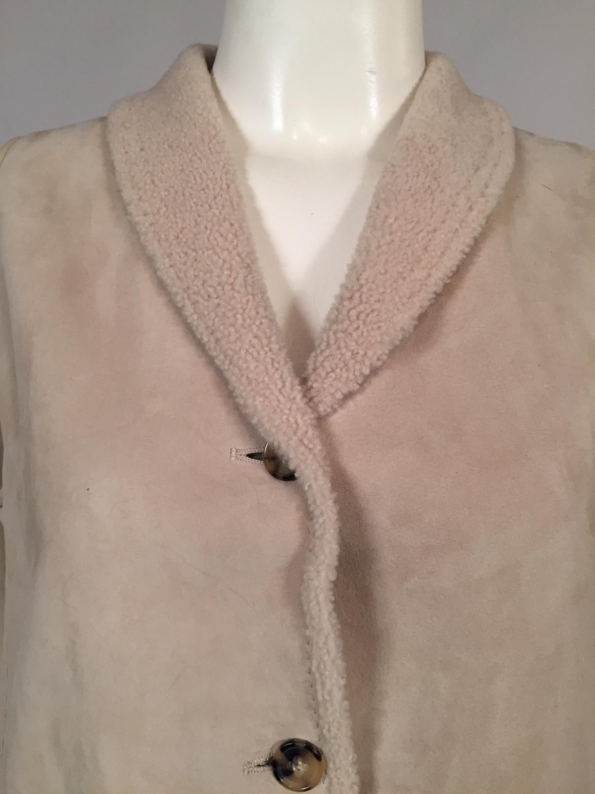 A light weight shearling vest is perfect for layering now and wearing alone when the temperatures begin to warm up. It has a shawl collar, four logo buttons, and there are pockets in the side seams. It is in excellent condition and appears to have