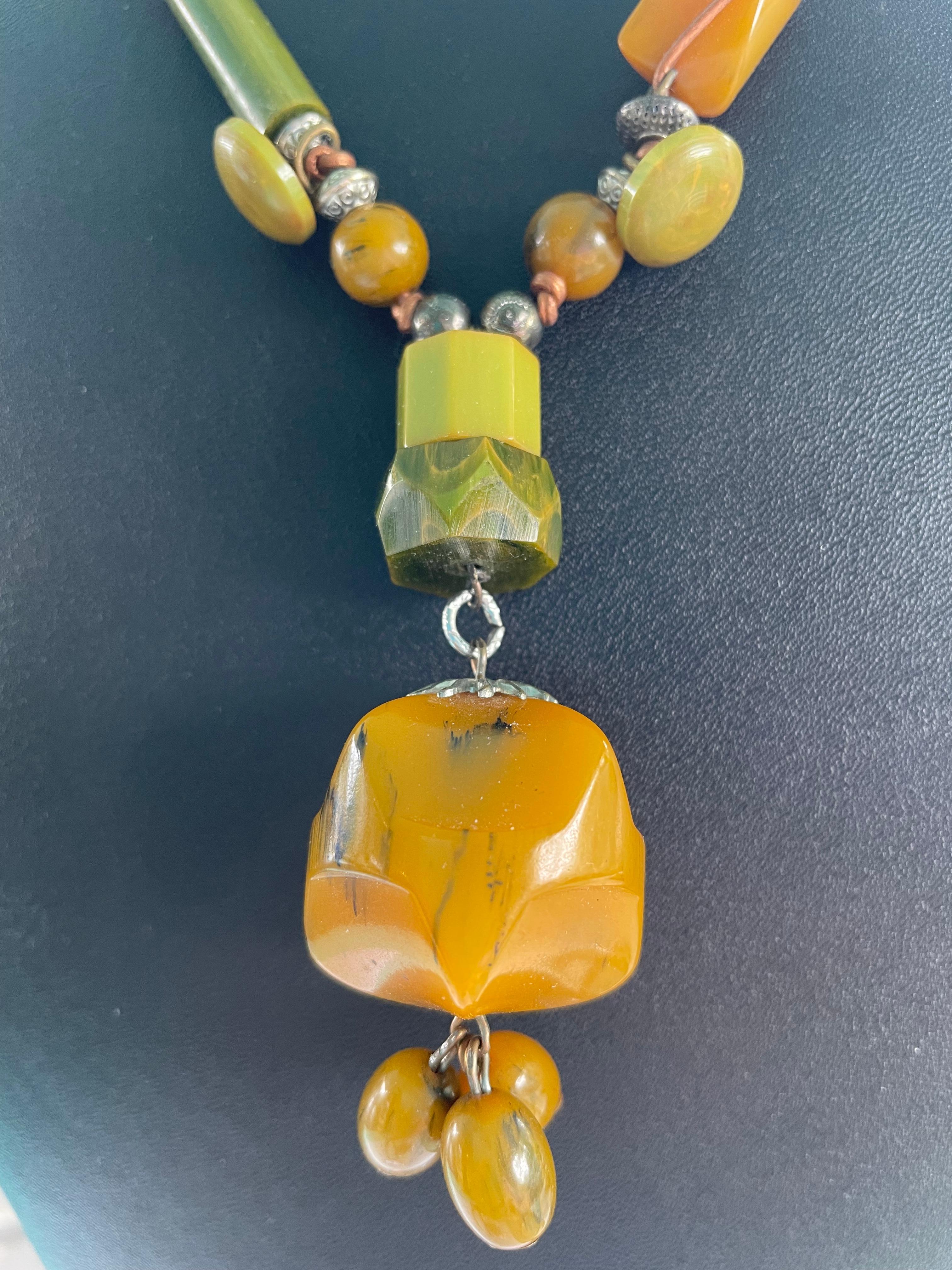 This statement necklace consists of all vintage Bakelite components. Many shades of green and gold(in several different shapes) are strung on copper leather cord.Silver beads are used as spacers and the clasp is sterling silver. 