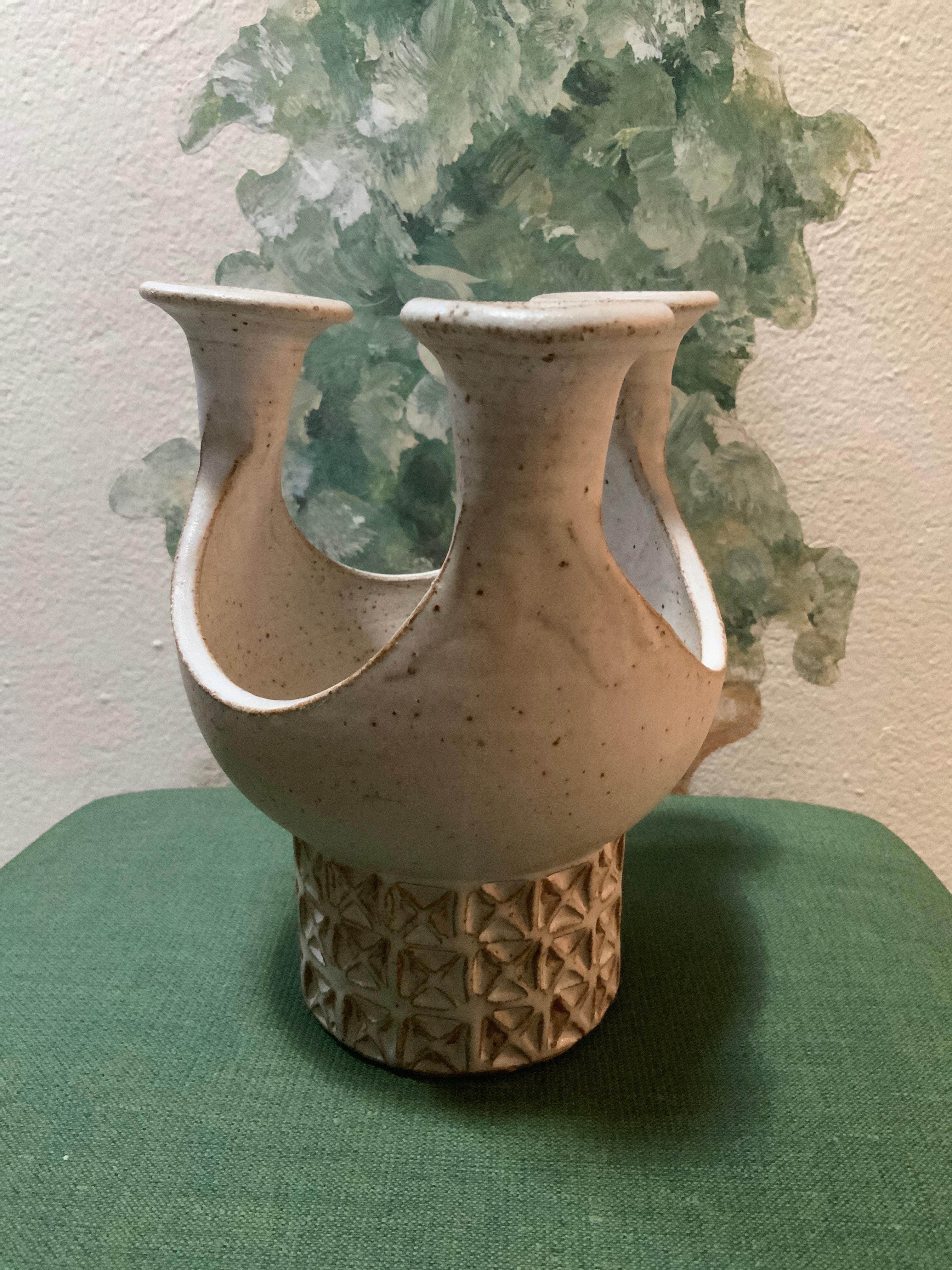 This is a Puerto Rican Los Artesanos Pottery Candleholder Centerpiece. It depicts a white three trumpet shaped arms candleholder with a center bowl like centerpiece. The base of the bowl is adorned woth a geometric pattern of squares and crosses.