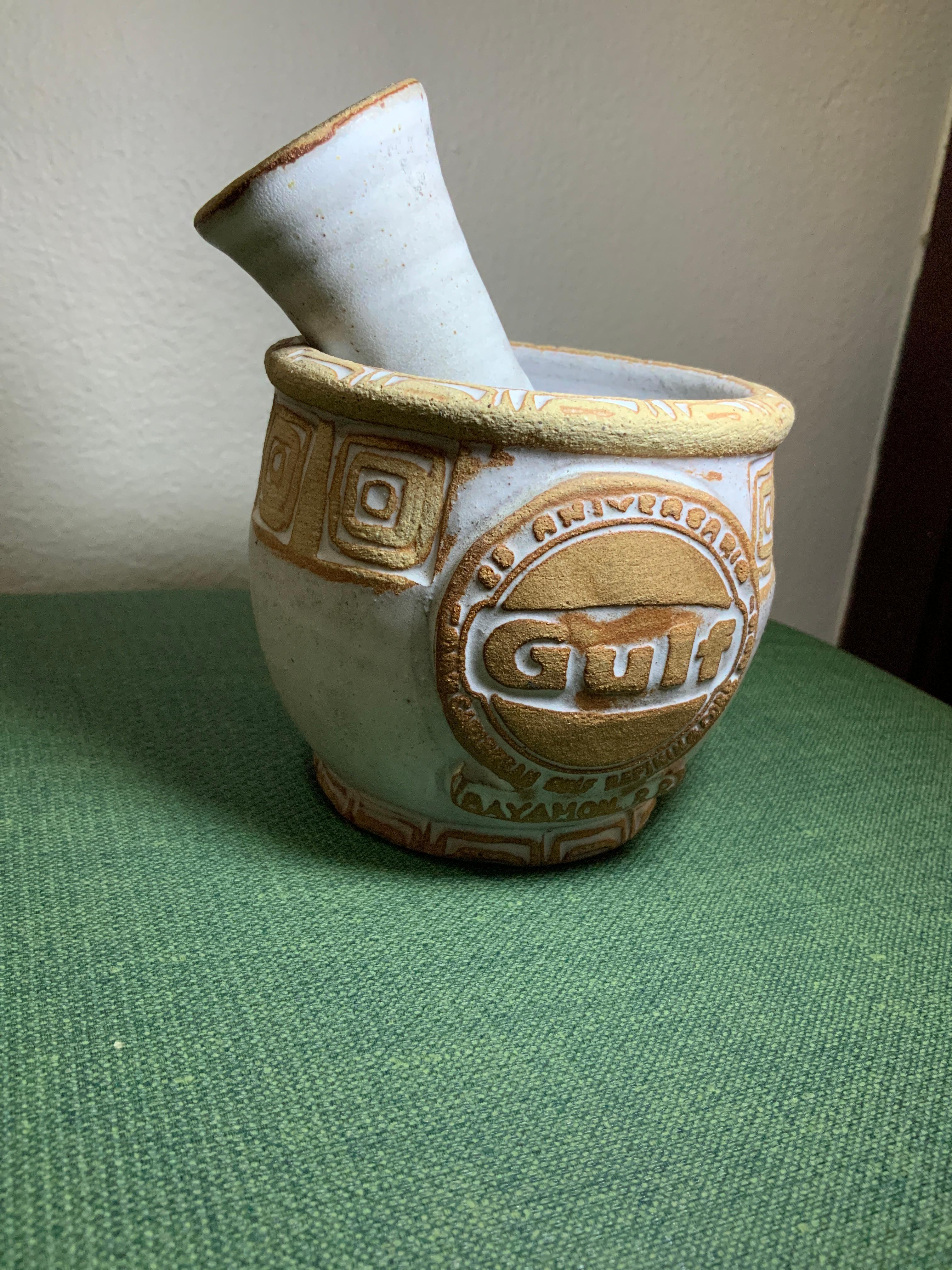 Il s'agit d'un mortier et d'un pilon de Los Artesanos Pottery Gulf Caribbean Oil Refining Company 25th Anniversary Edition. Whiting représente un petit mortier blanc en forme de bol rond, dont la bordure supérieure et la base sont ornées d'un motif