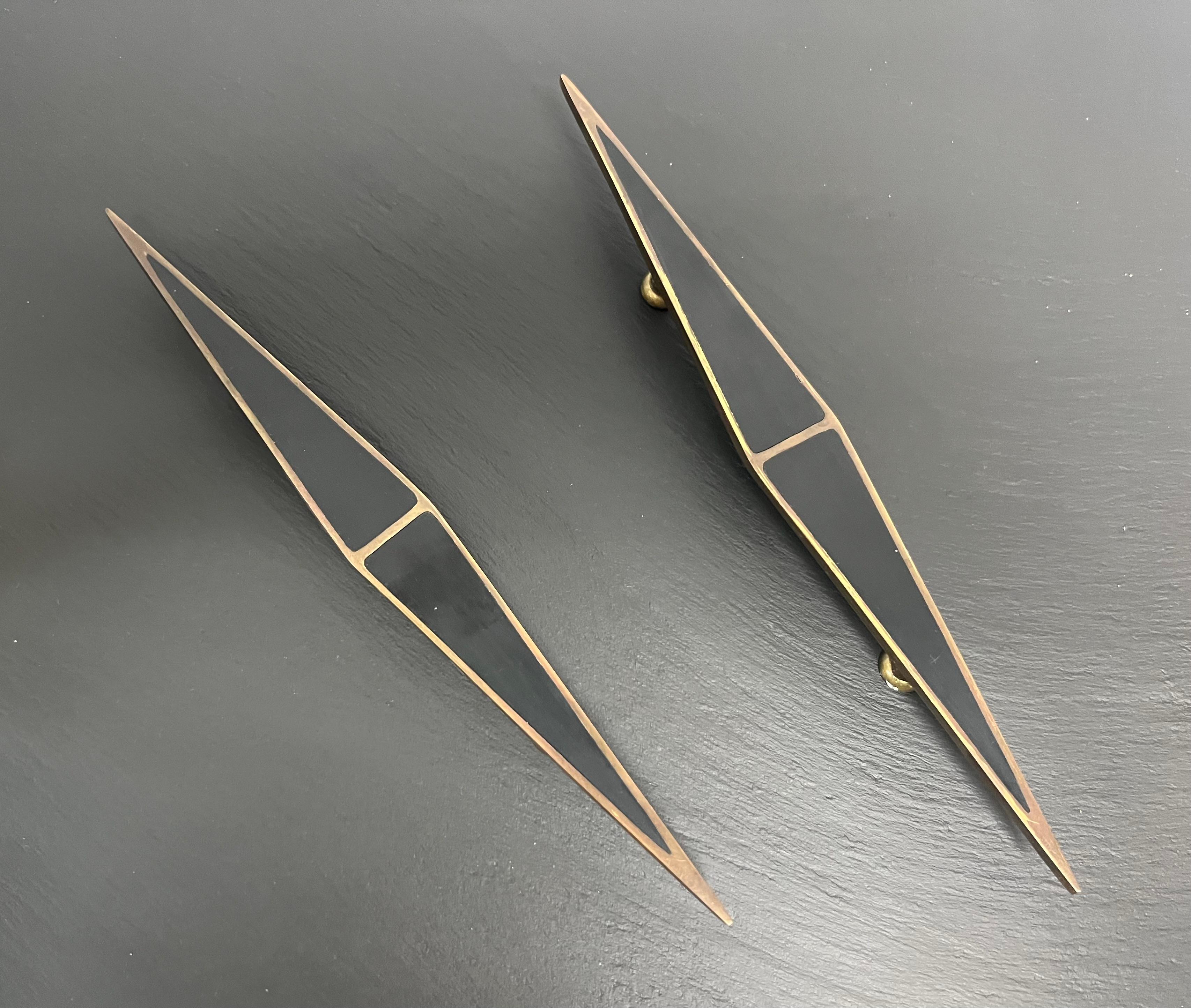 Elegant and sculptural pair of cabinet pulls by Los Castillo, Taxco, Mexico, circa 1950s. Each handle is hand-crafted in solid brass with bold geometric inlay in black resin or onyx, forming a striking contrast of material and color. The elongated