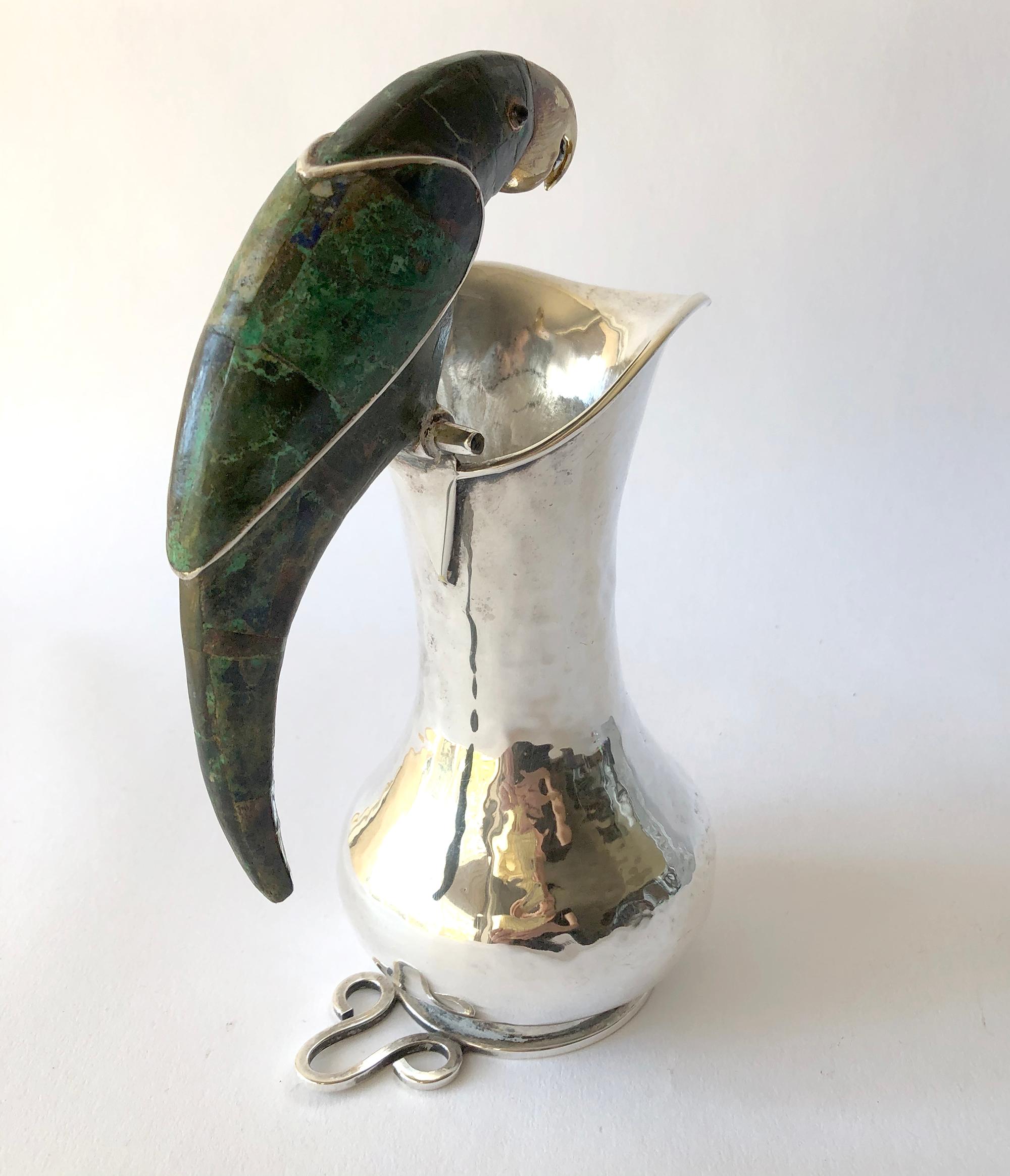 Hammered silver plate pitcher with azurite and malachite inlay parrot handle created by the Los Castillo workshop, Taxco, Mexico circa 1960s. Pitcher measures 7.5